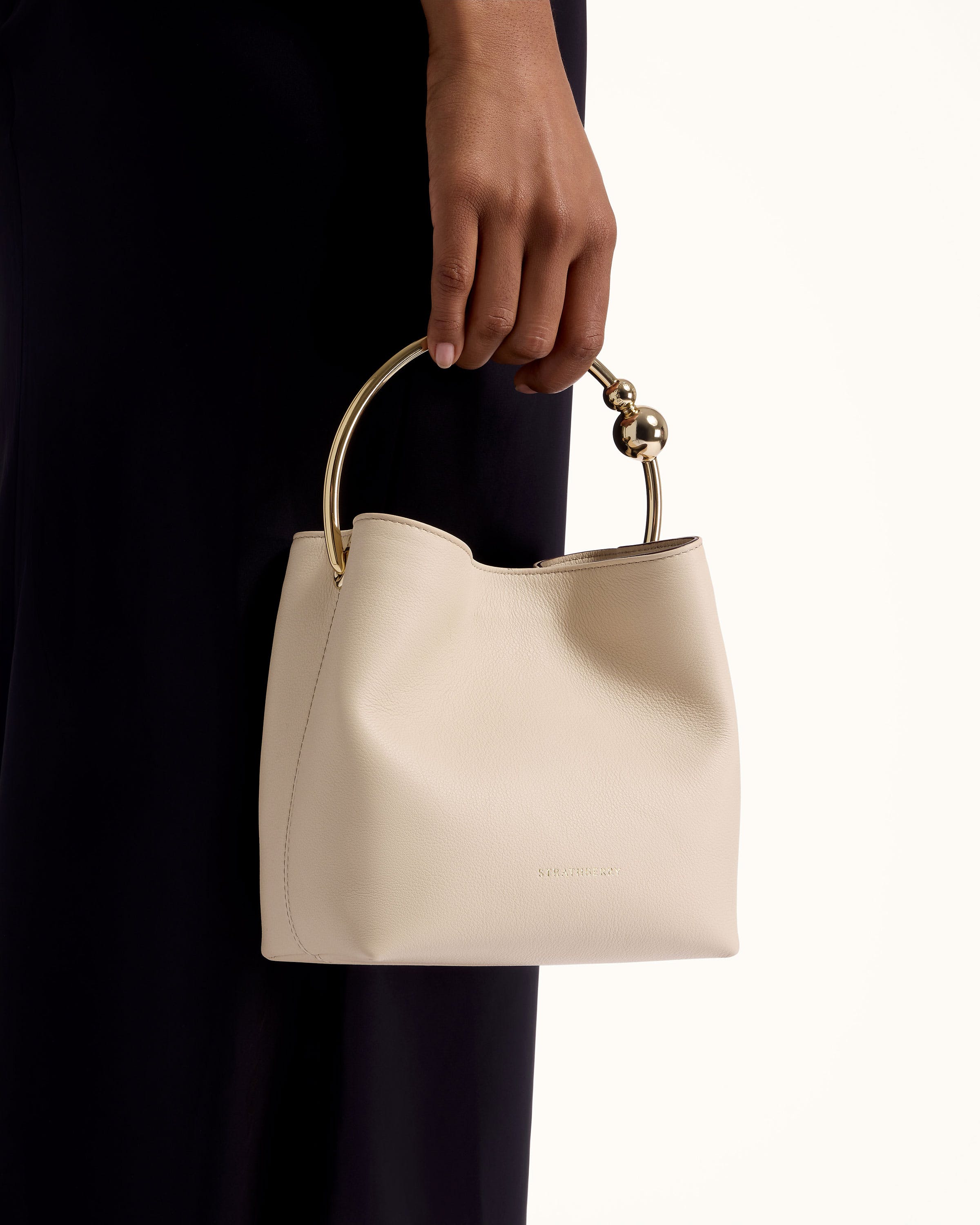 A woman holding a white purse with a gold handle