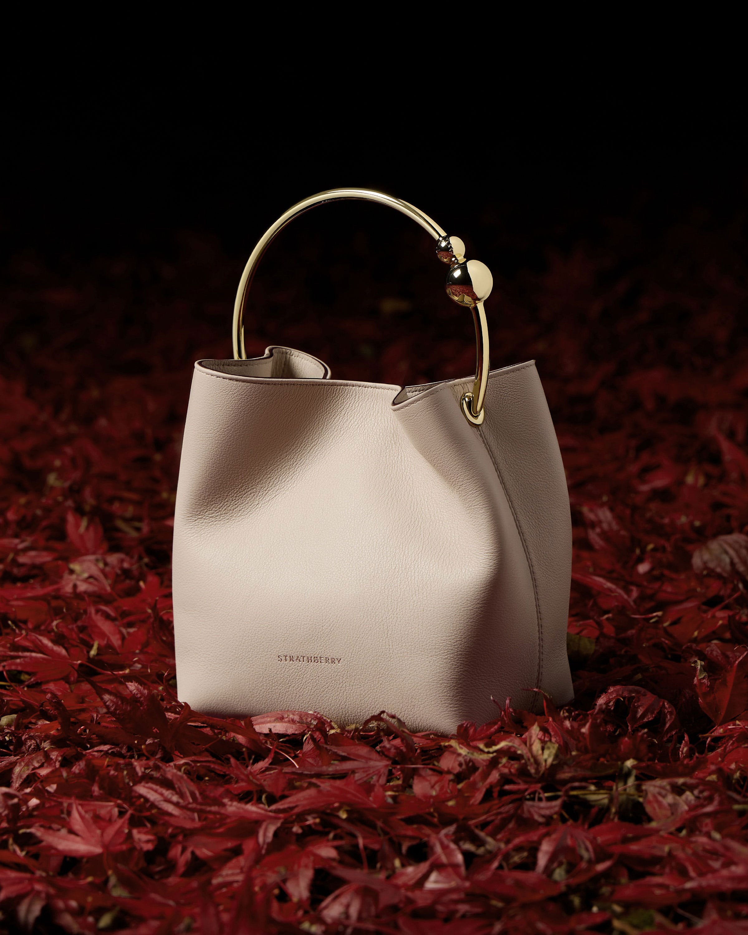 A white purse sitting on top of a pile of red leaves