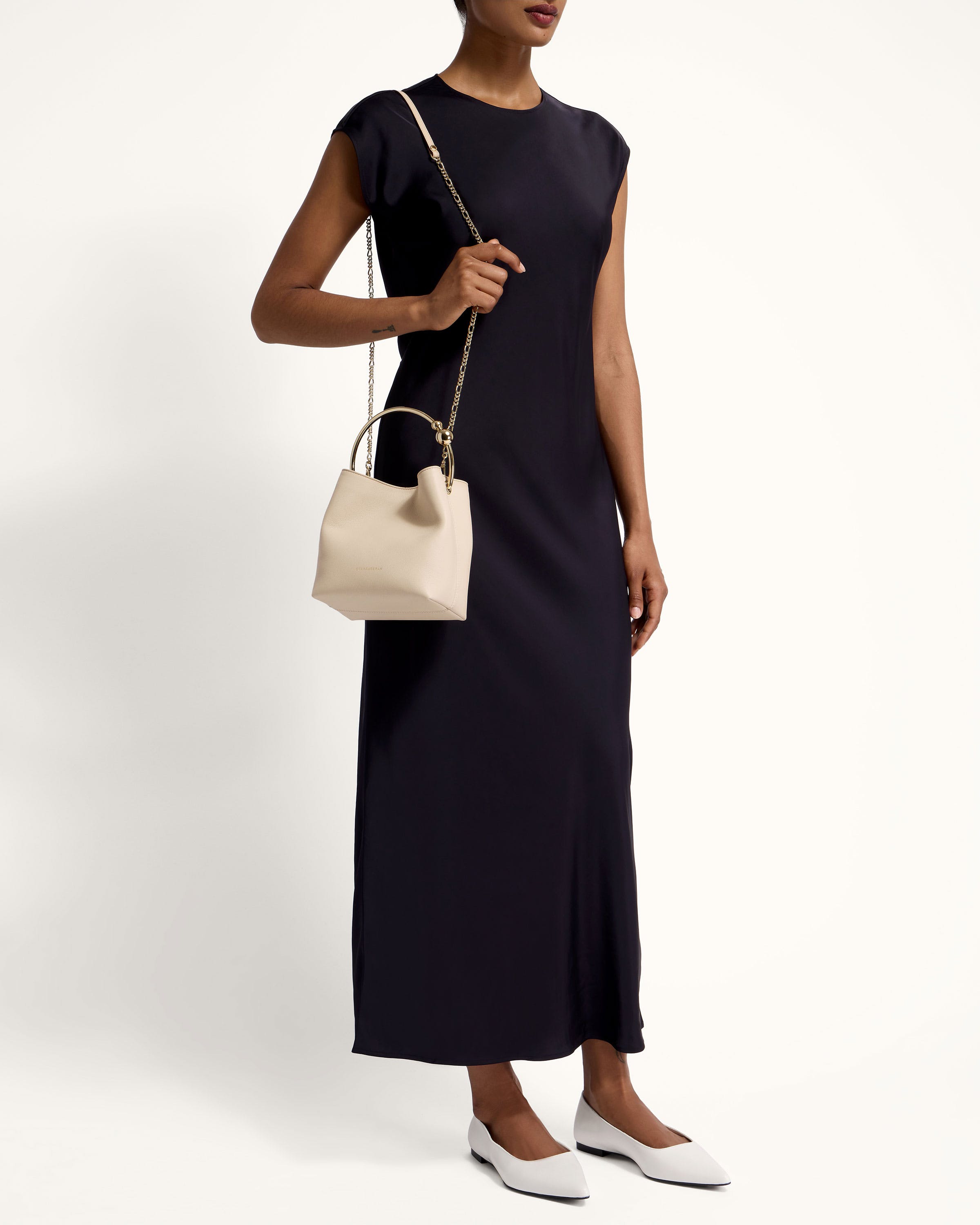 A woman in a black dress holding a white purse