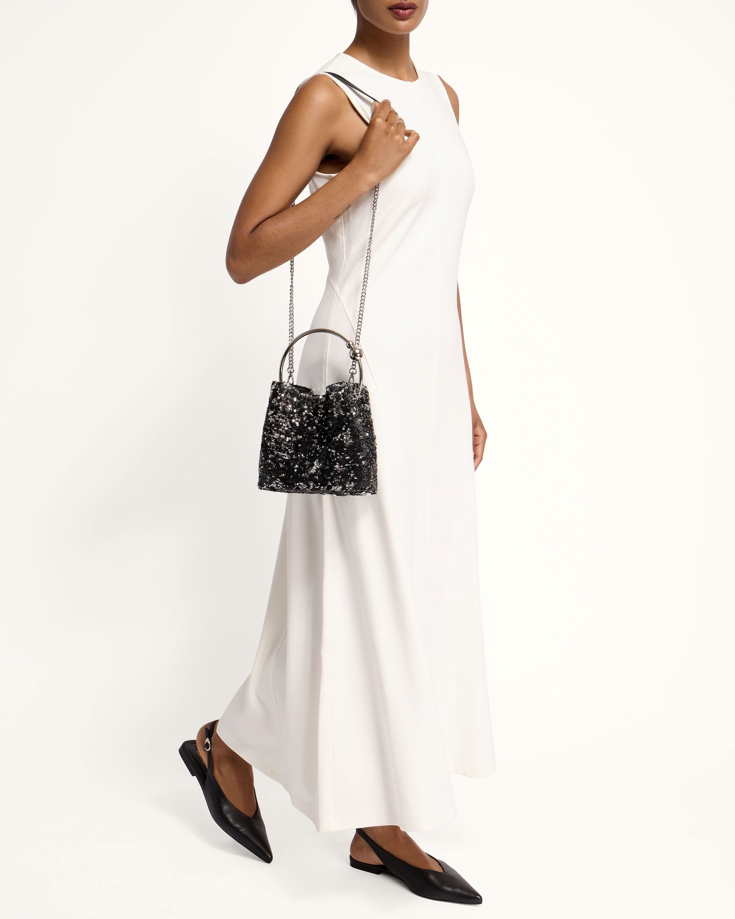 A woman in a white dress holding a black purse