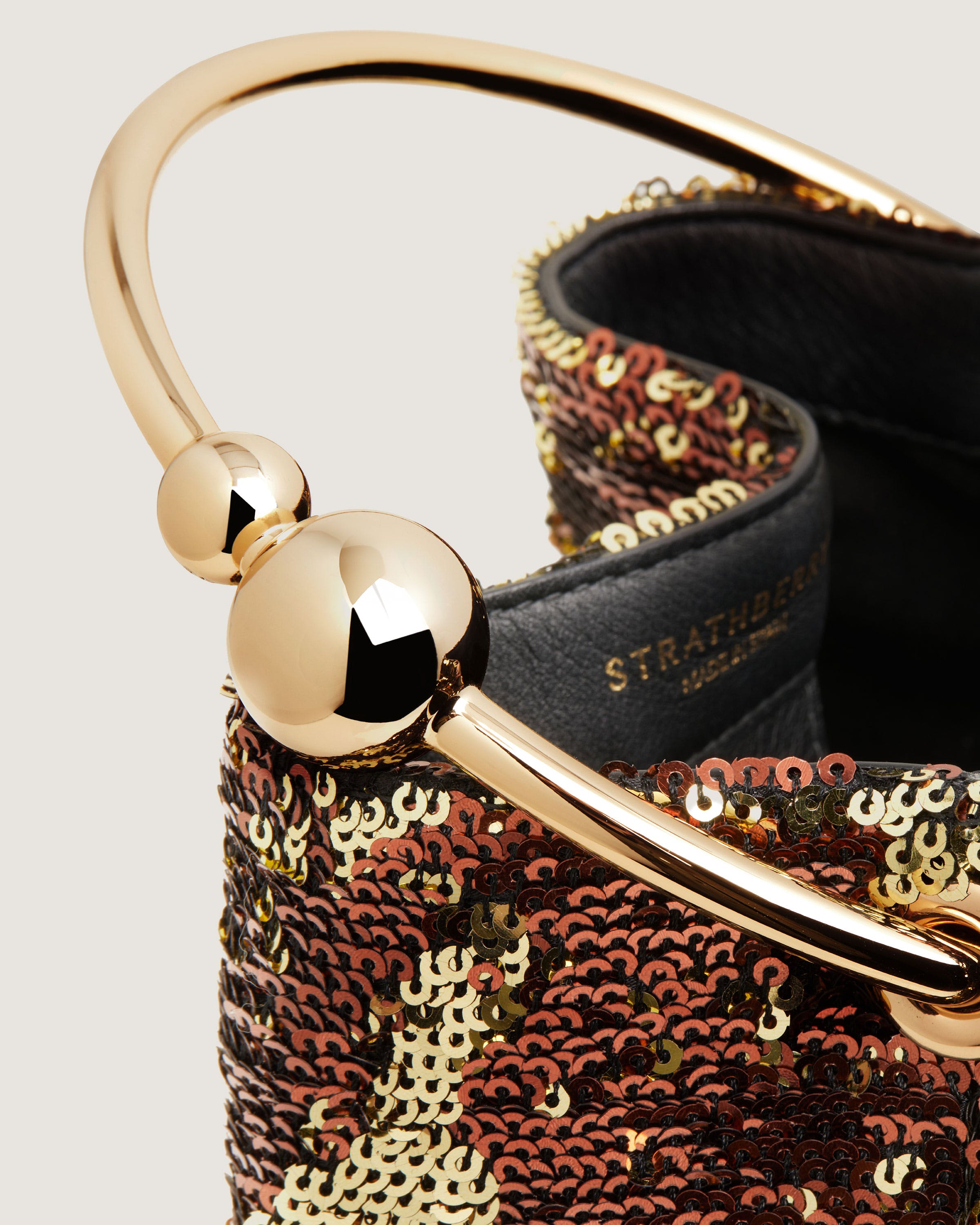 A handbag with a gold handle and sequins