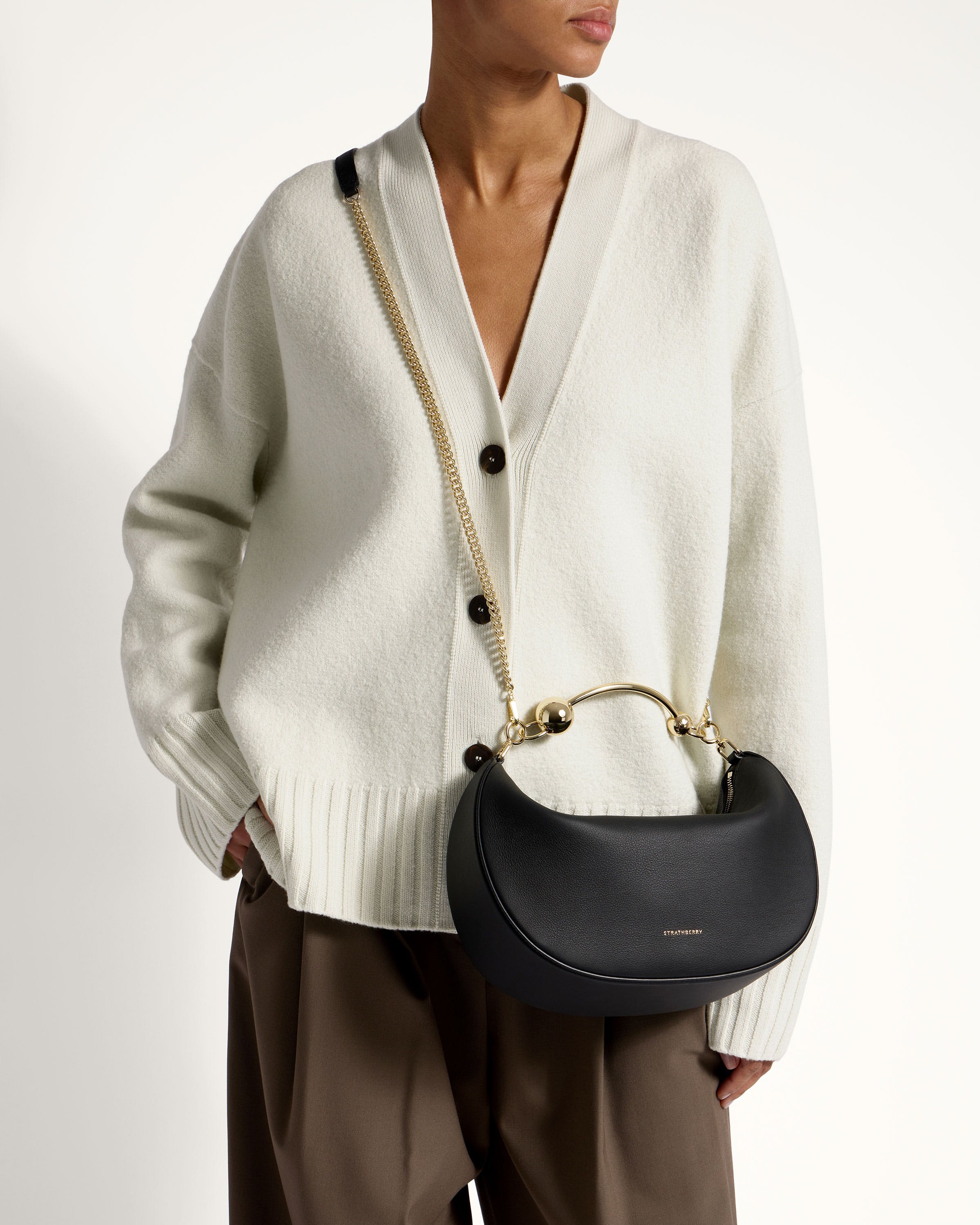 A woman in a white sweater holding a black purse