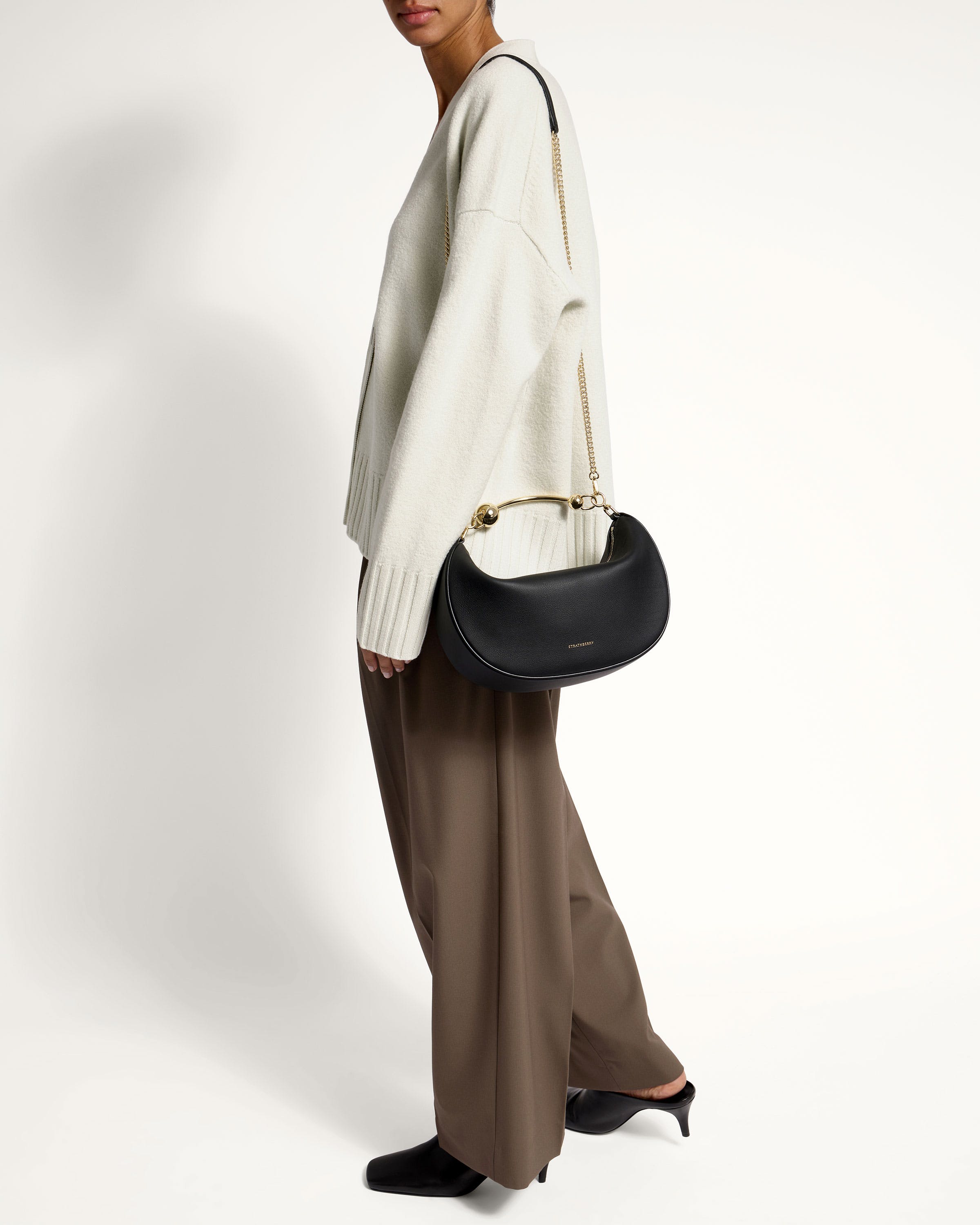 A woman in a white sweater holding a black handbag