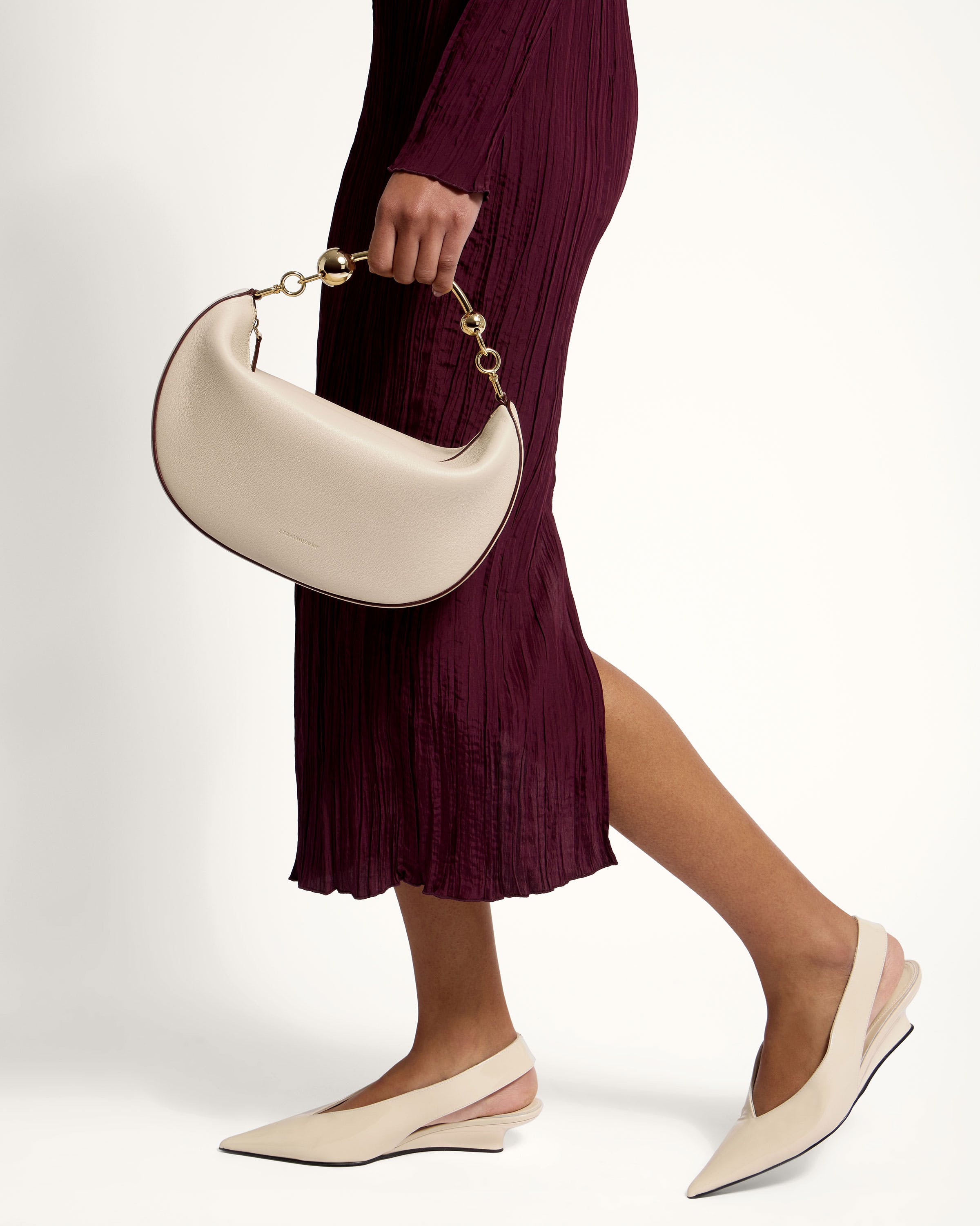 A woman in a maroon dress carrying a white purse