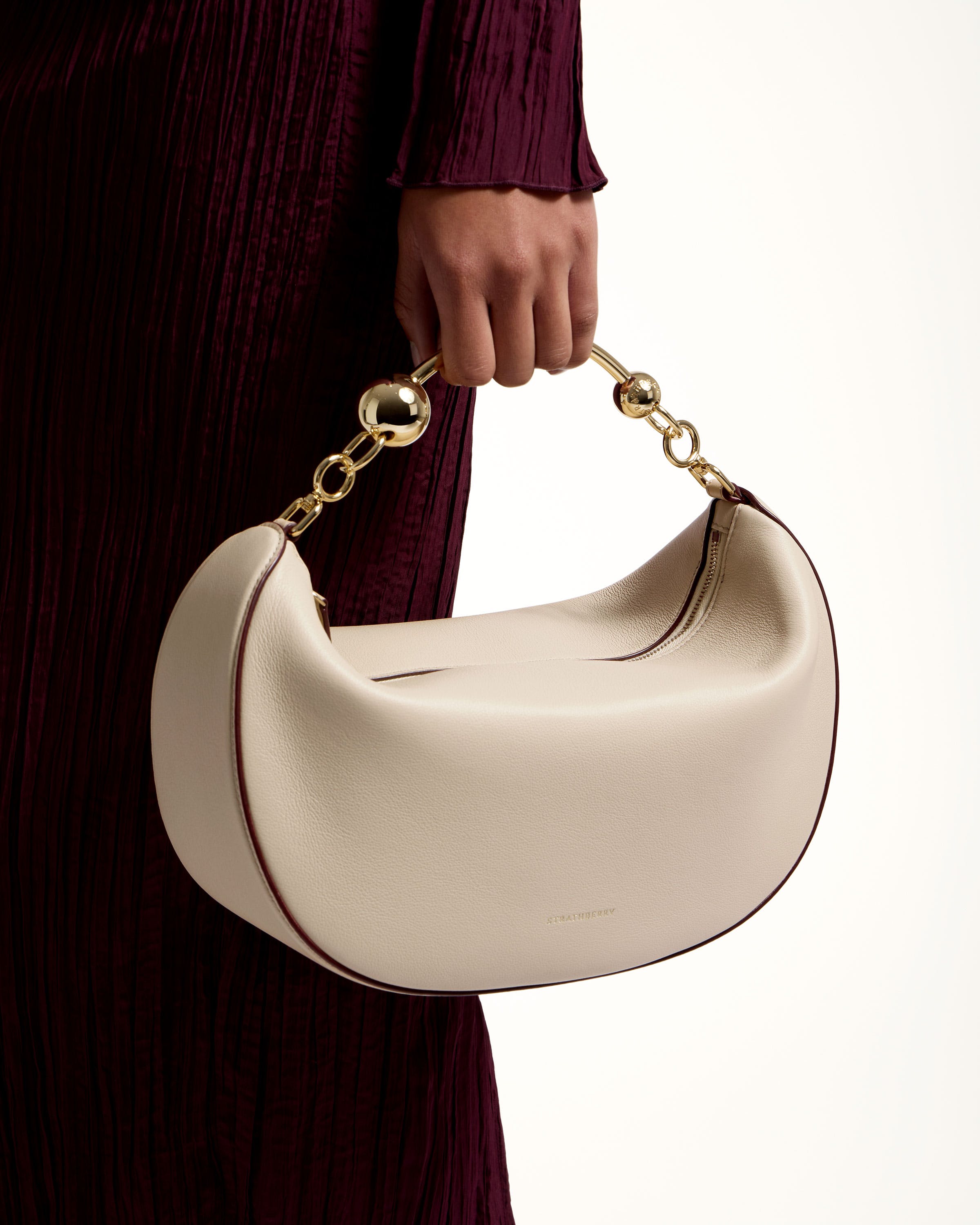 A woman holding a white purse with a gold chain