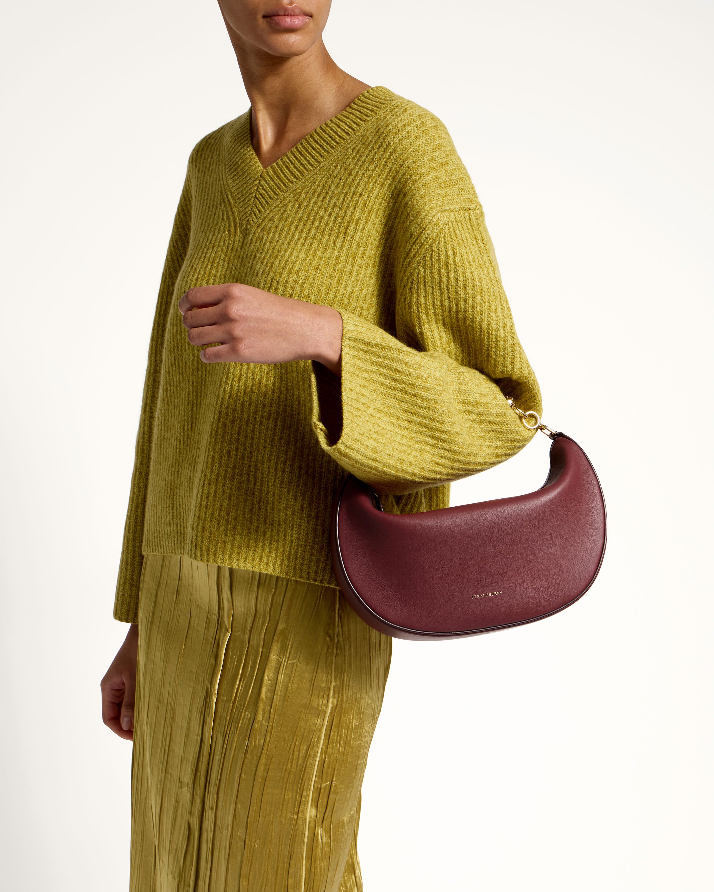 A woman in a green sweater holding a red purse