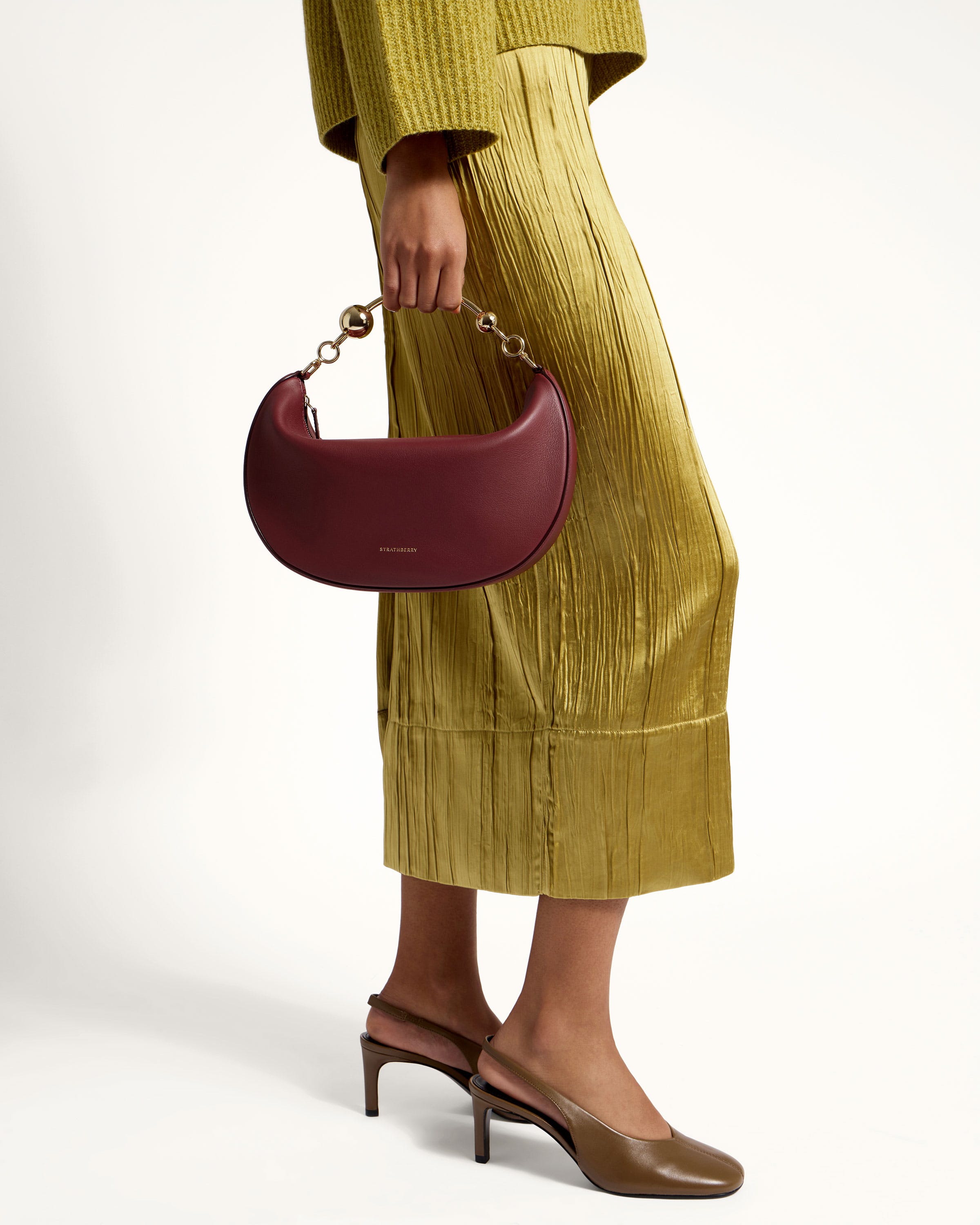 A woman in a yellow dress holding a burgundy purse