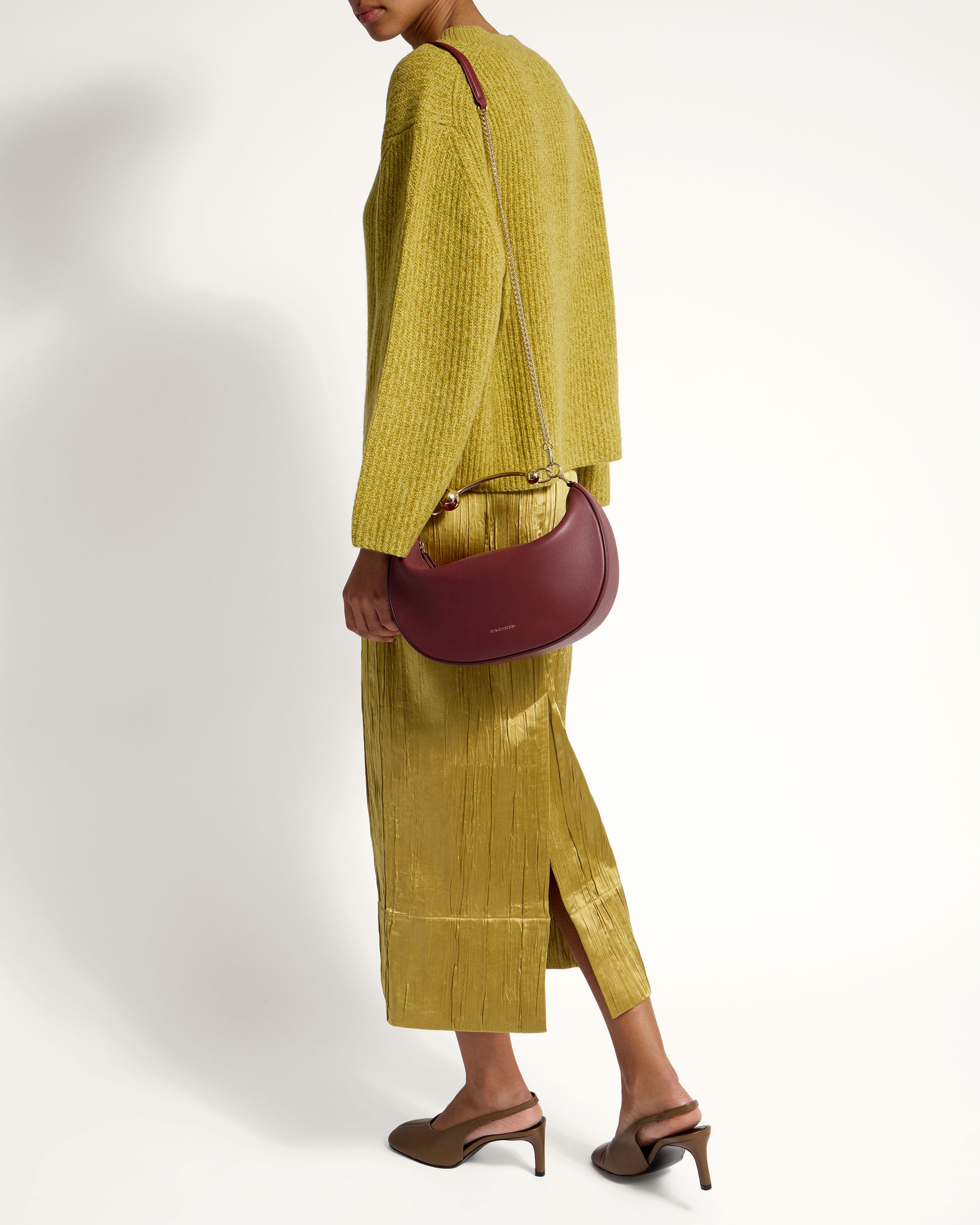 A woman in a yellow dress holding a red purse