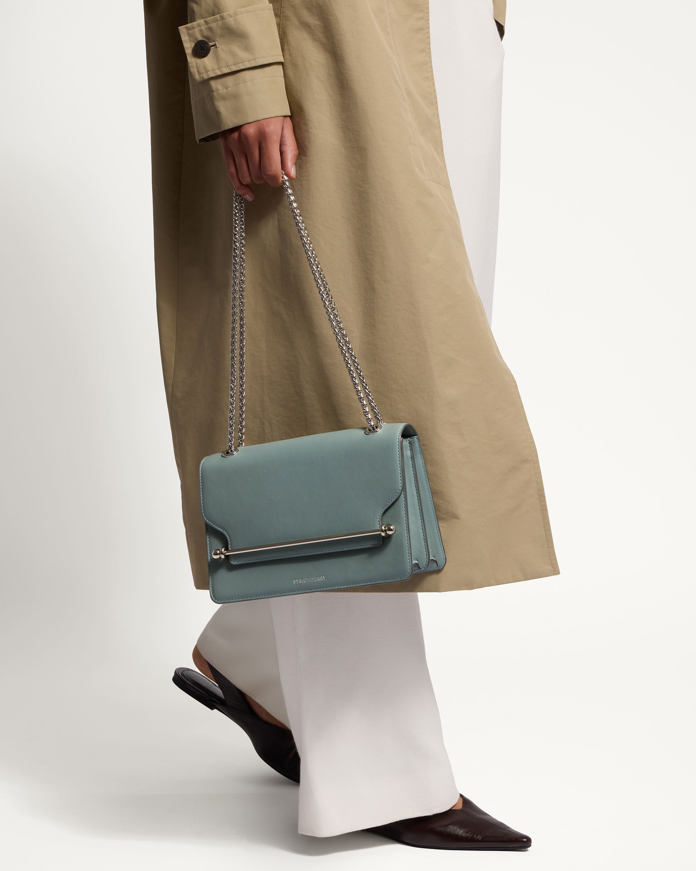 A woman in a trench coat carrying a blue purse