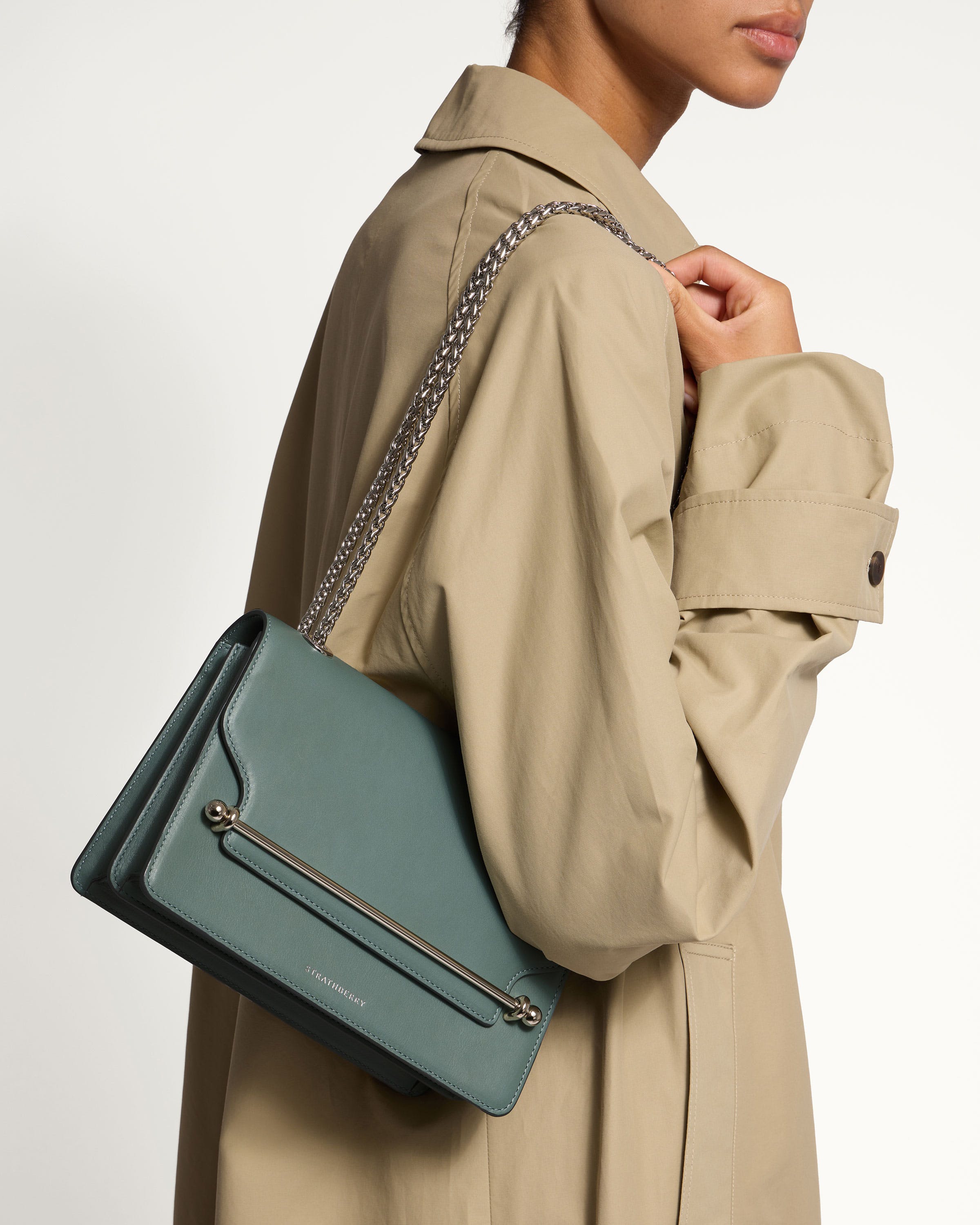 A woman in a trench coat holding a blue purse