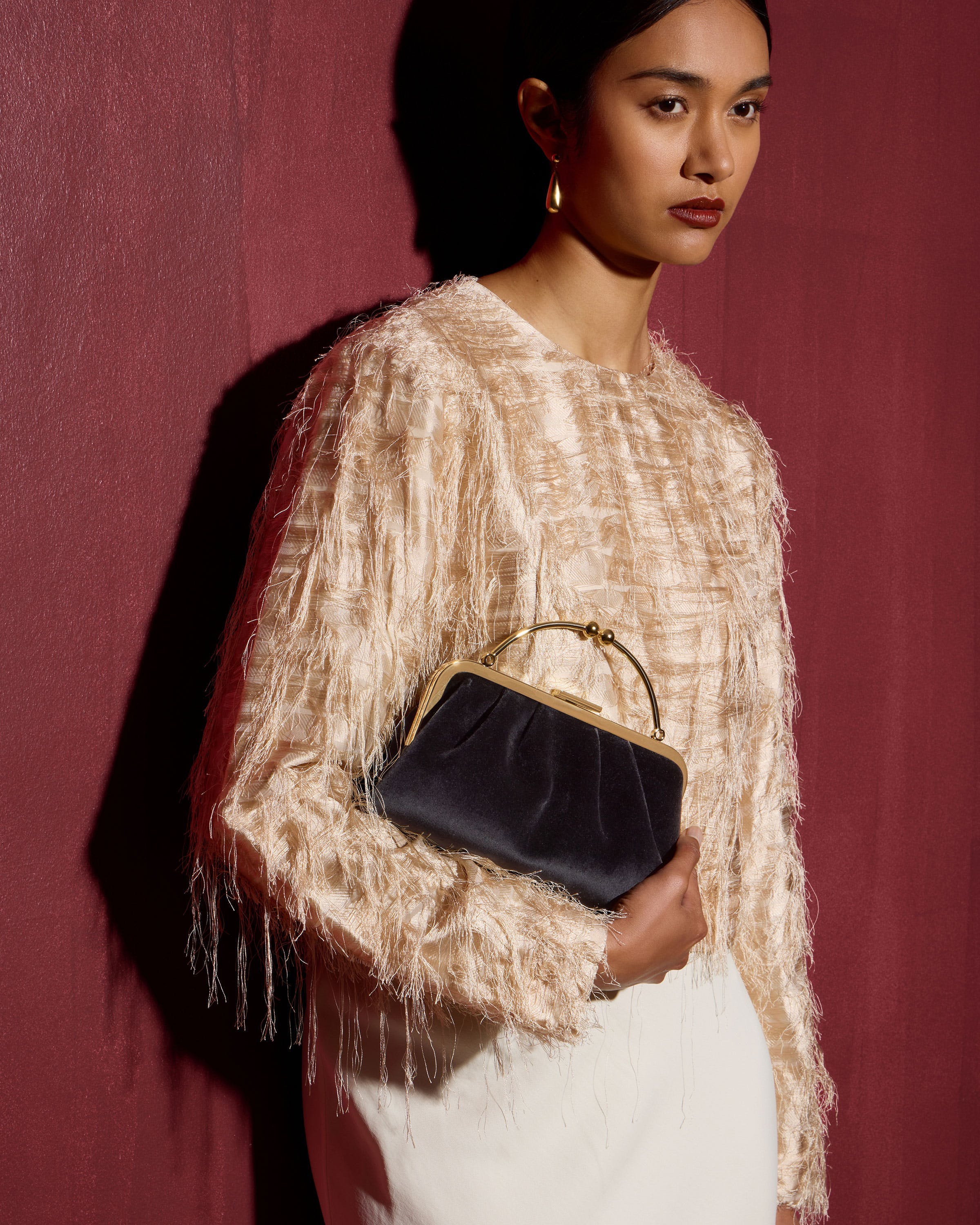 A woman in a white dress holding a black purse