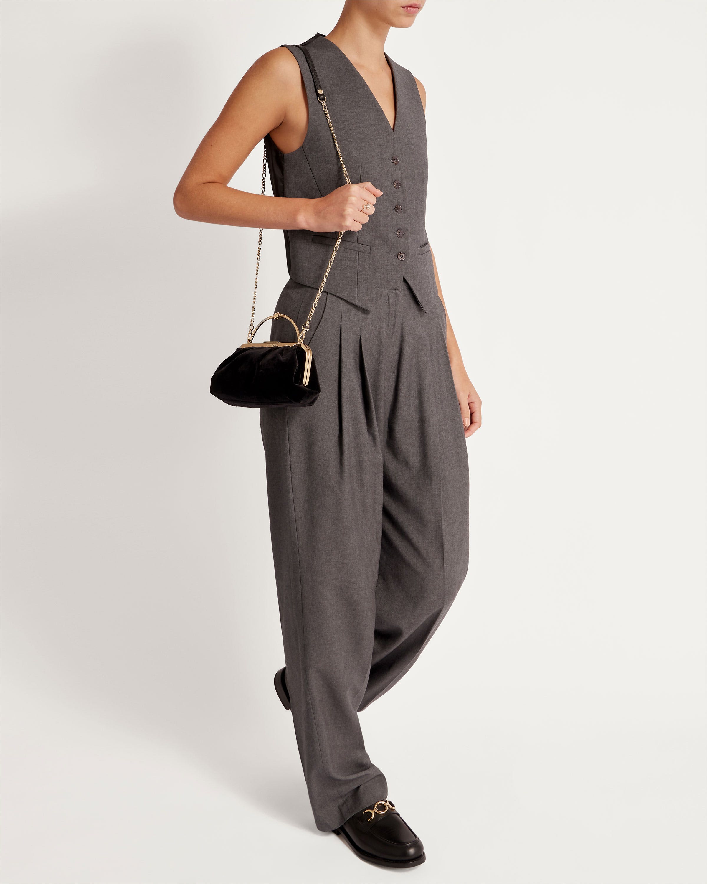 A woman in a gray jumpsuit holding a black purse