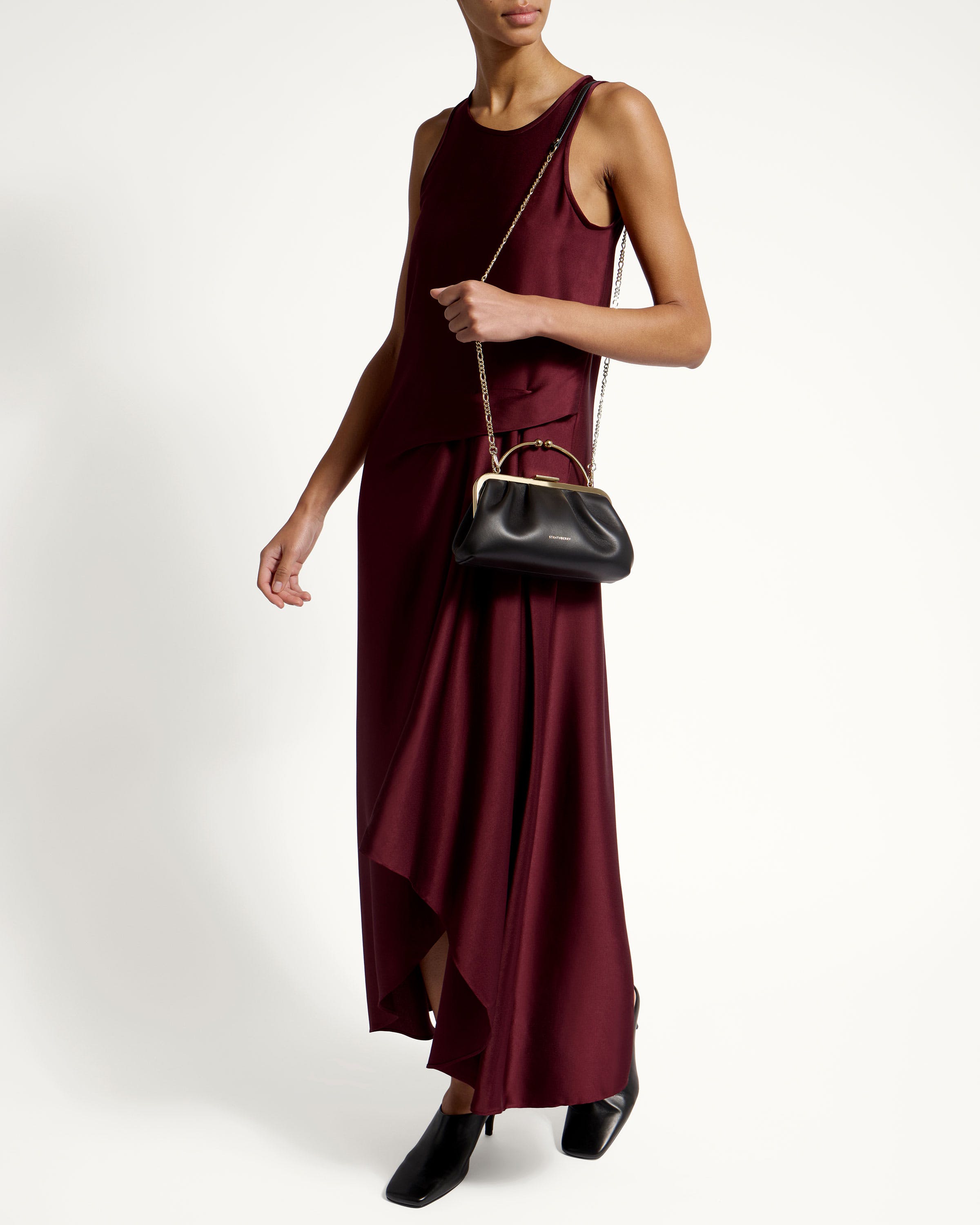 A woman in a maroon dress holding a black purse