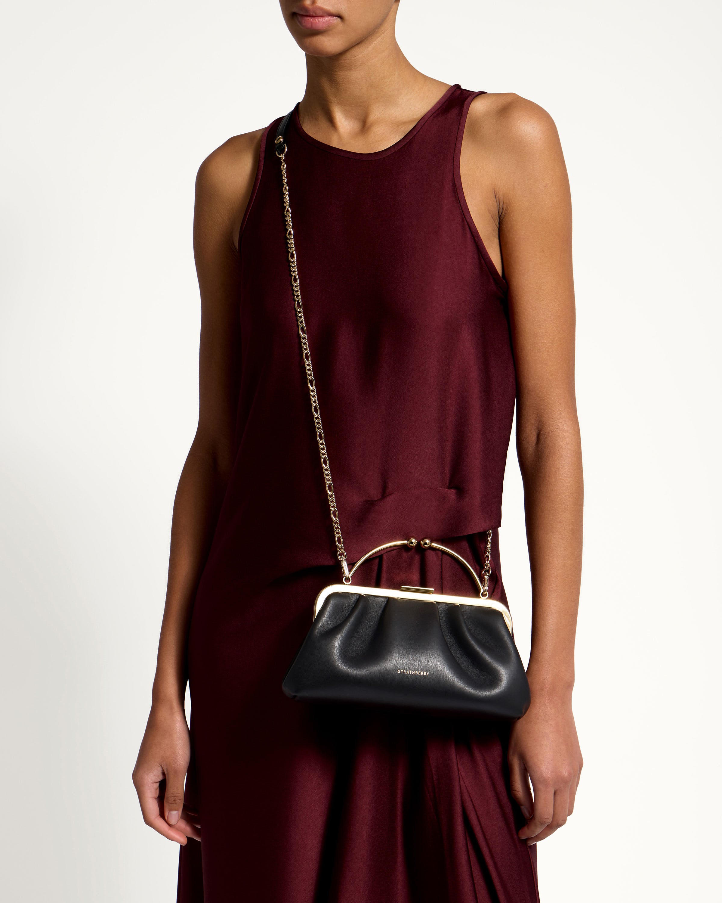 A woman in a maroon dress holding a black purse