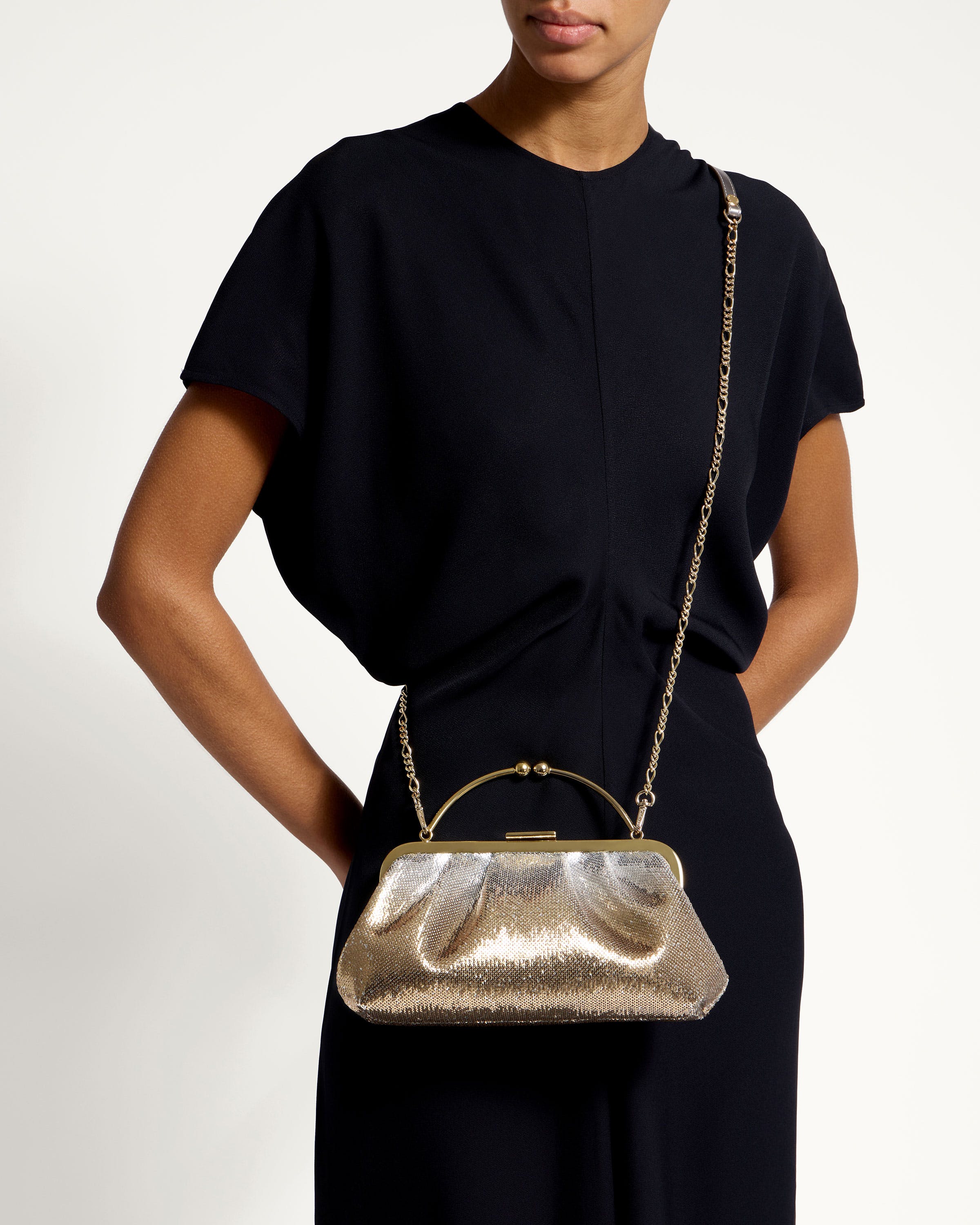 A woman in a black dress holding a gold purse