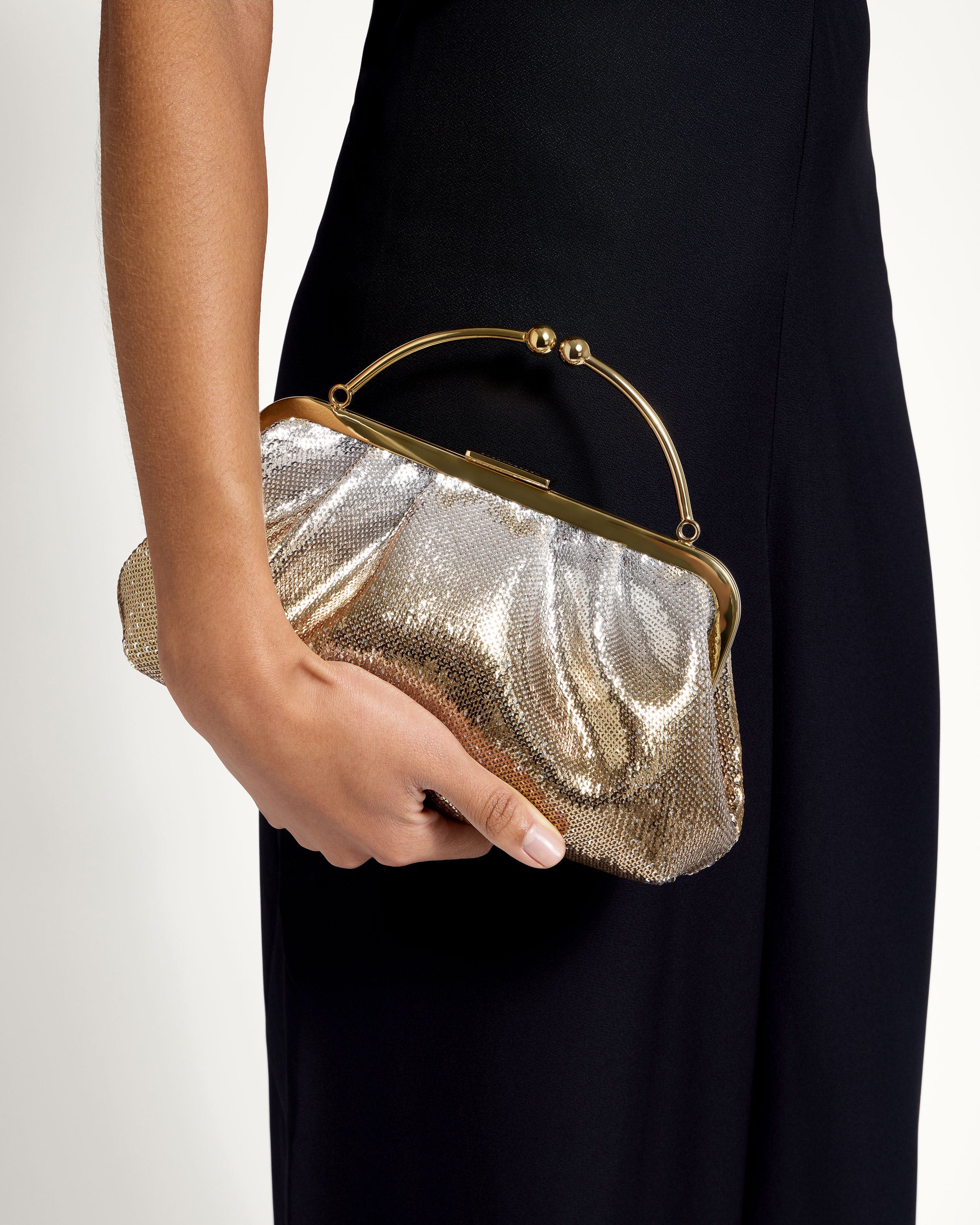 A woman in a black dress holding a gold purse