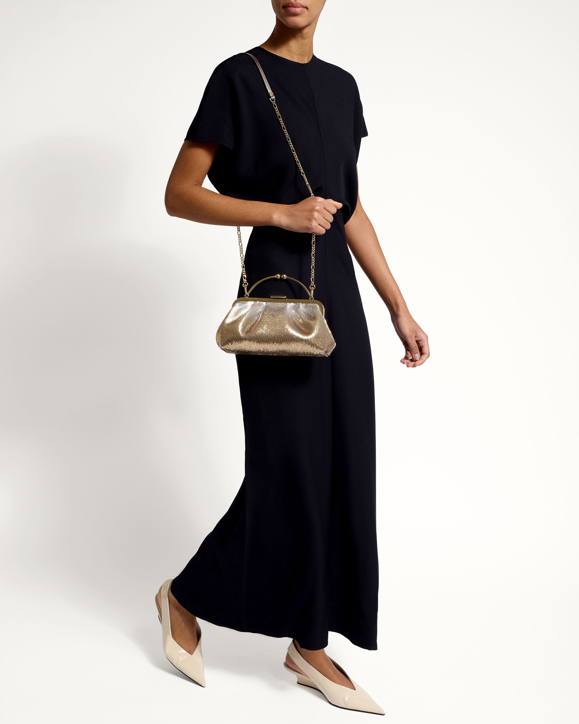 A woman in a black dress holding a gold purse