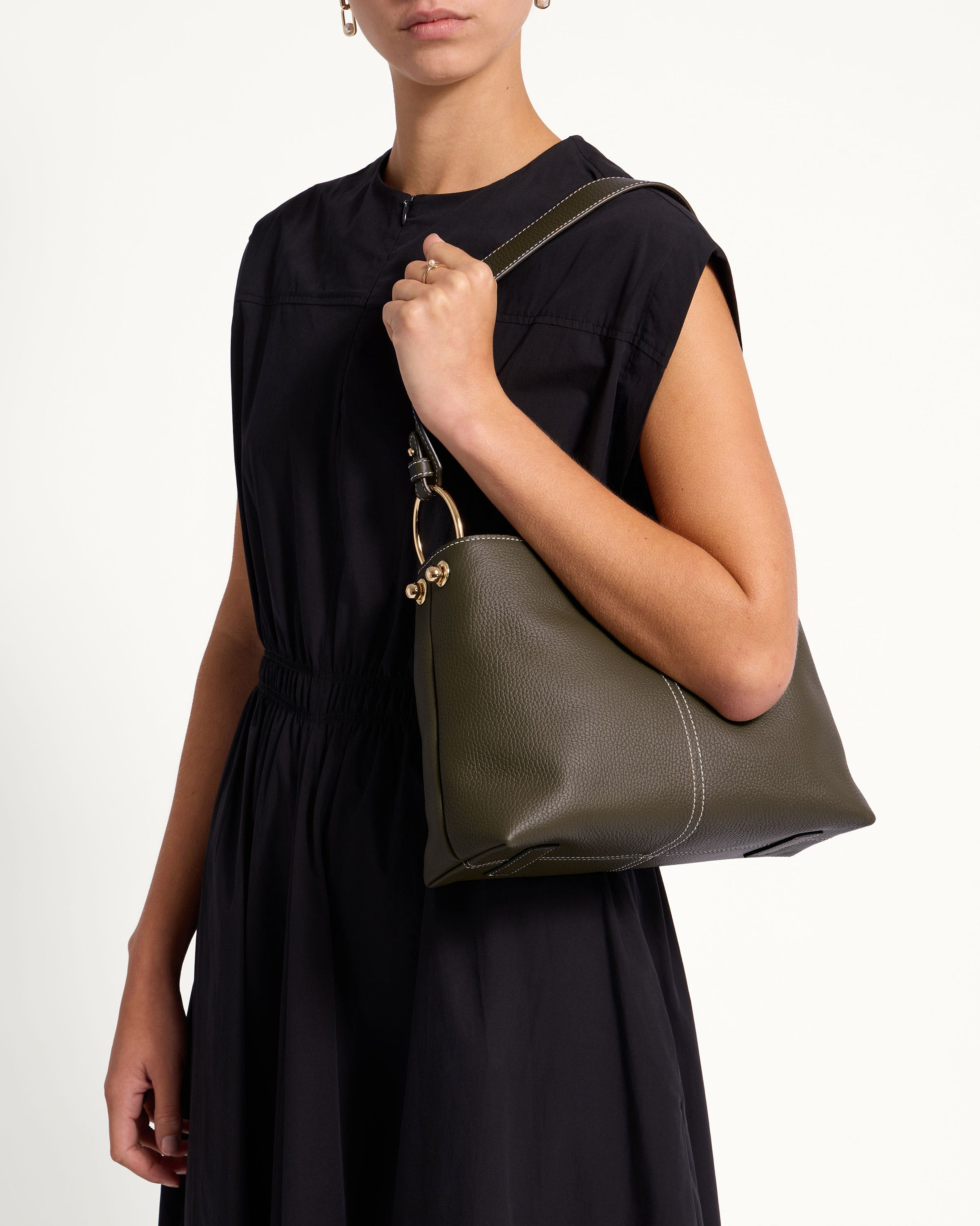 A woman in a black dress holding a green purse