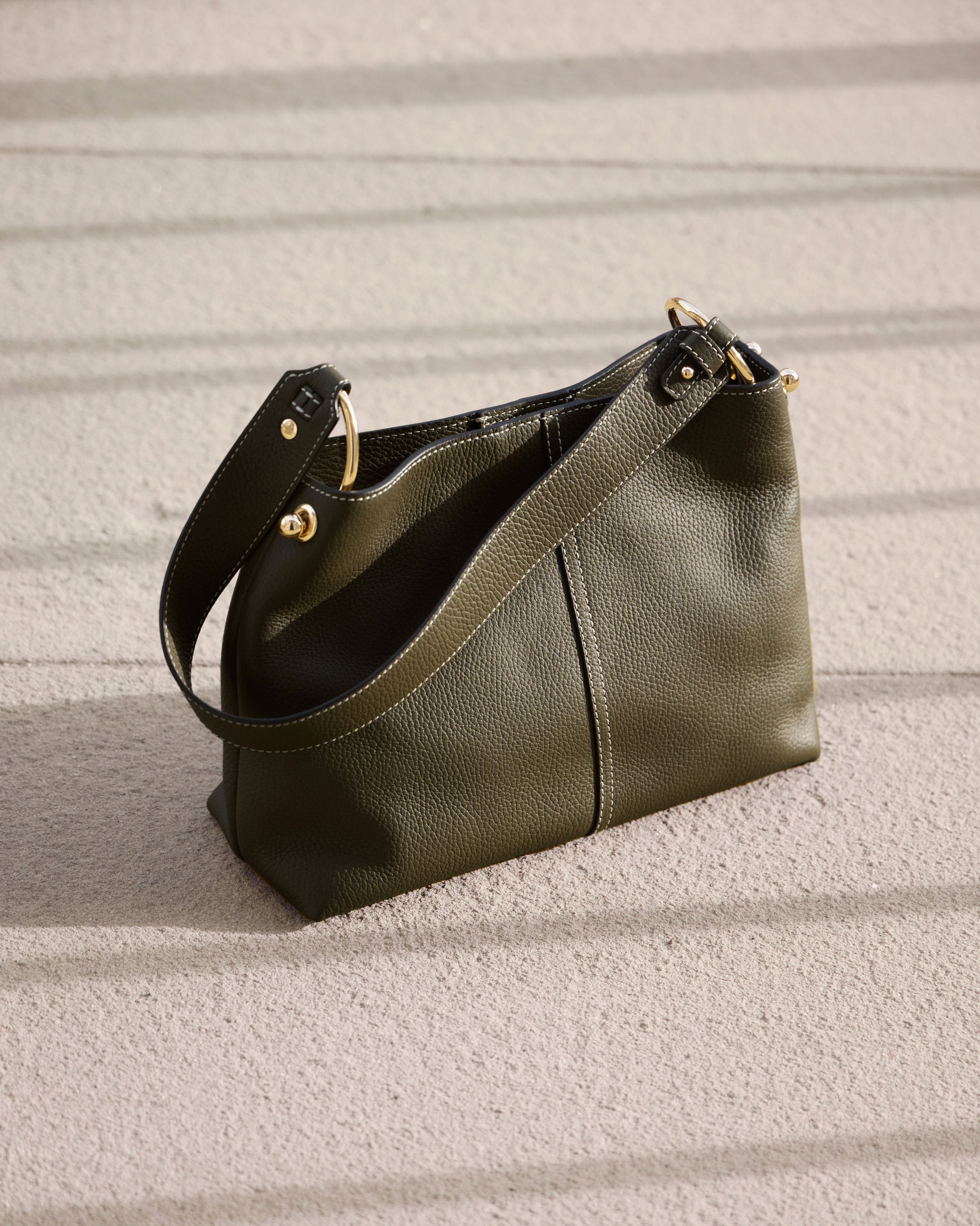 A green purse sitting on top of a sandy beach