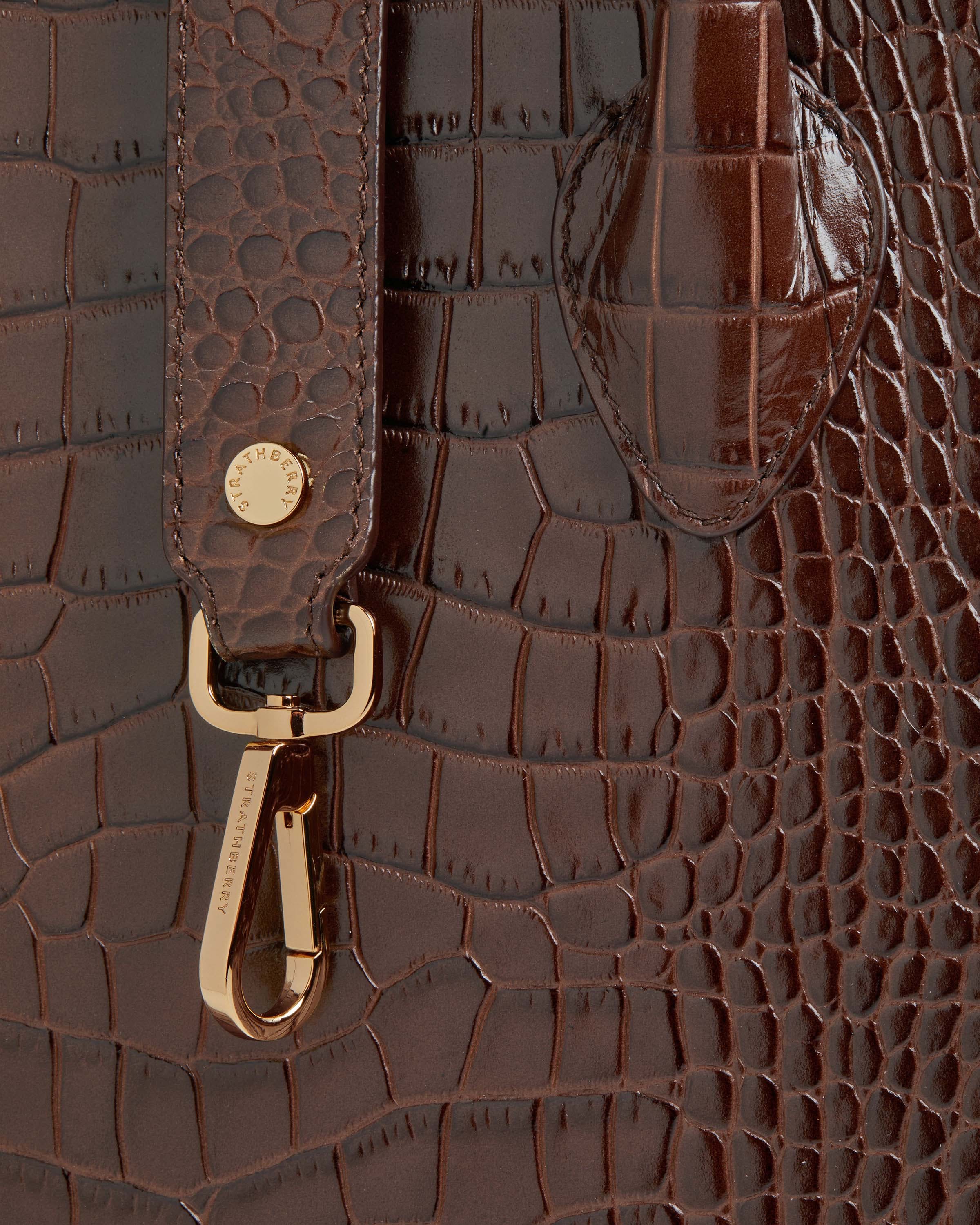 A close up of a brown alligator skin purse