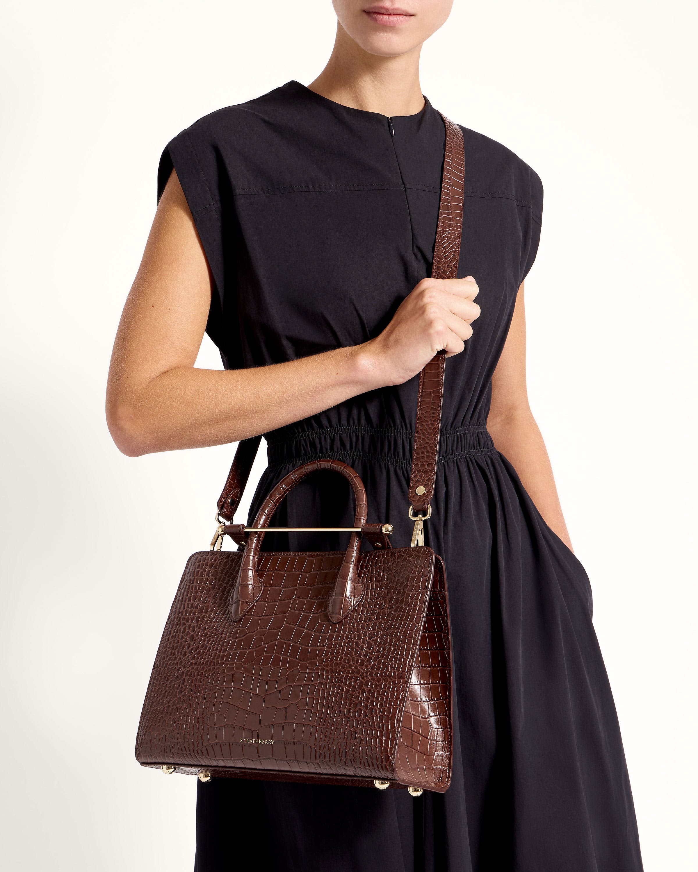 A woman in a black dress holding a brown handbag