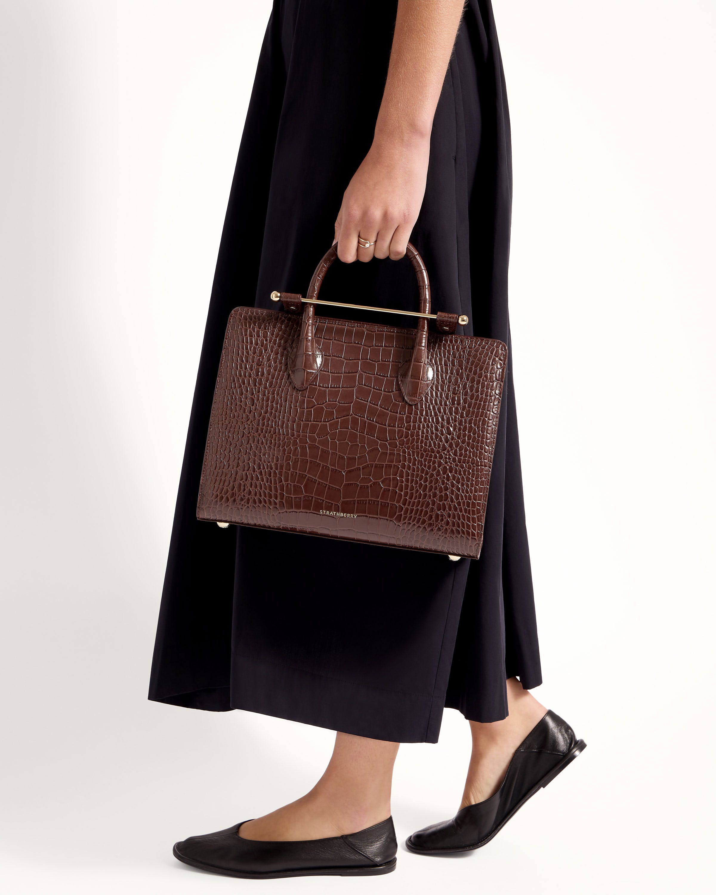 A woman in a black dress holding a brown bag