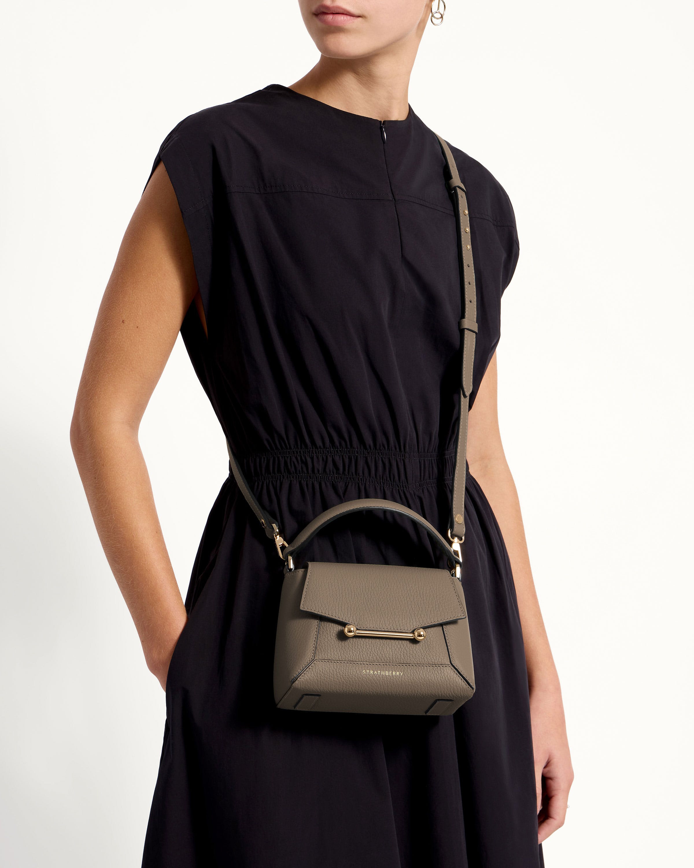 A woman in a black dress holding a gray purse