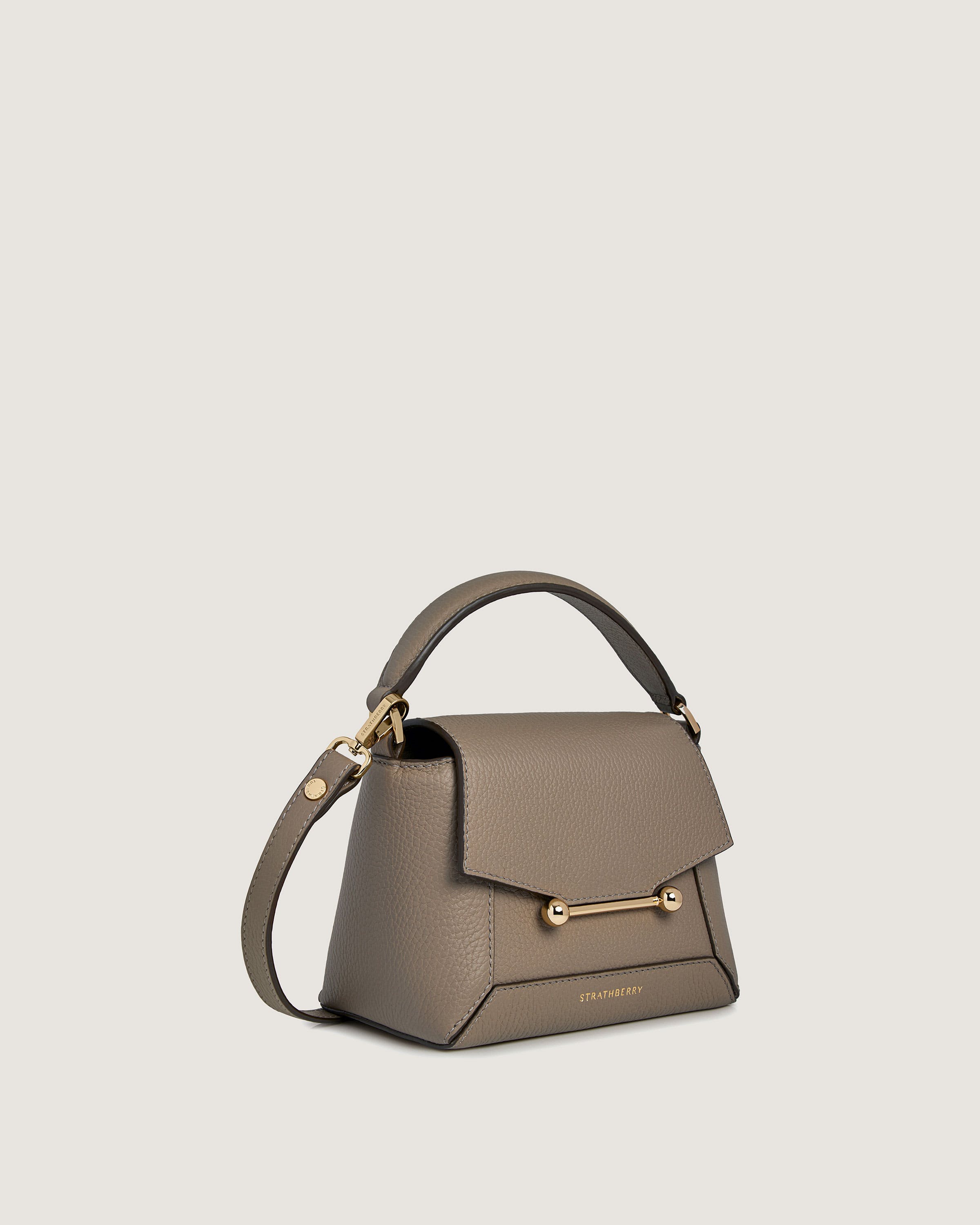 A grey handbag with a gold handle