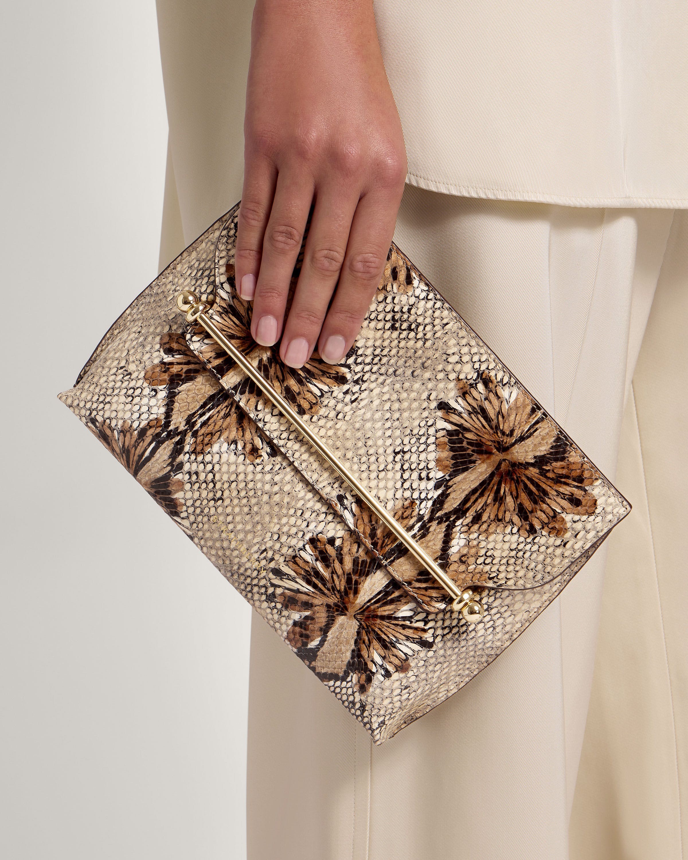 A woman's hand is holding a snake skin purse