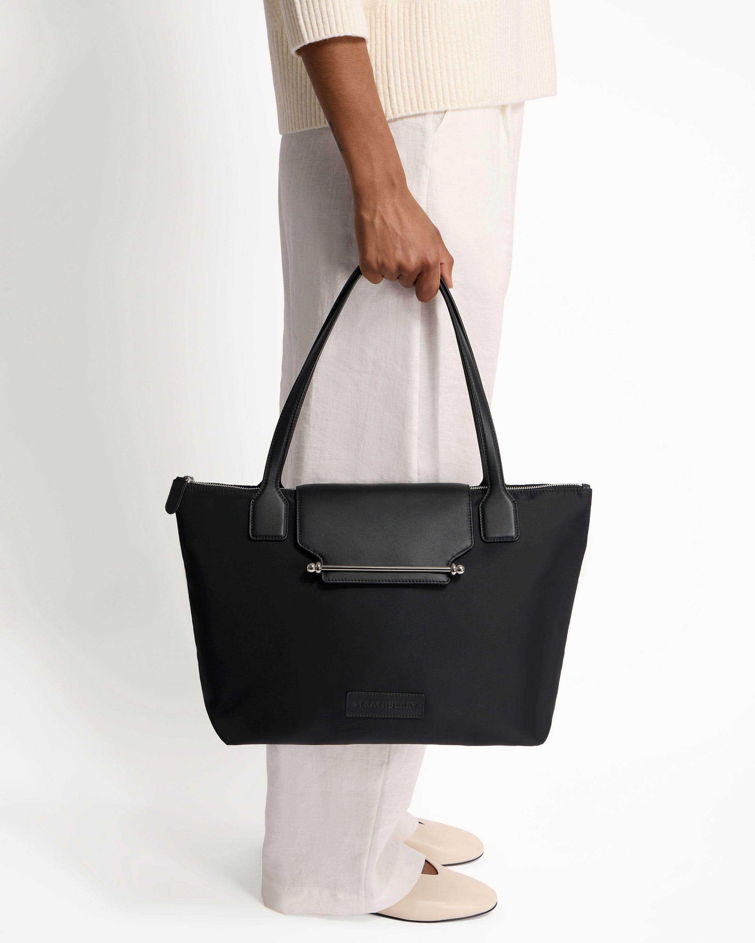 A person holding a black bag on a white background