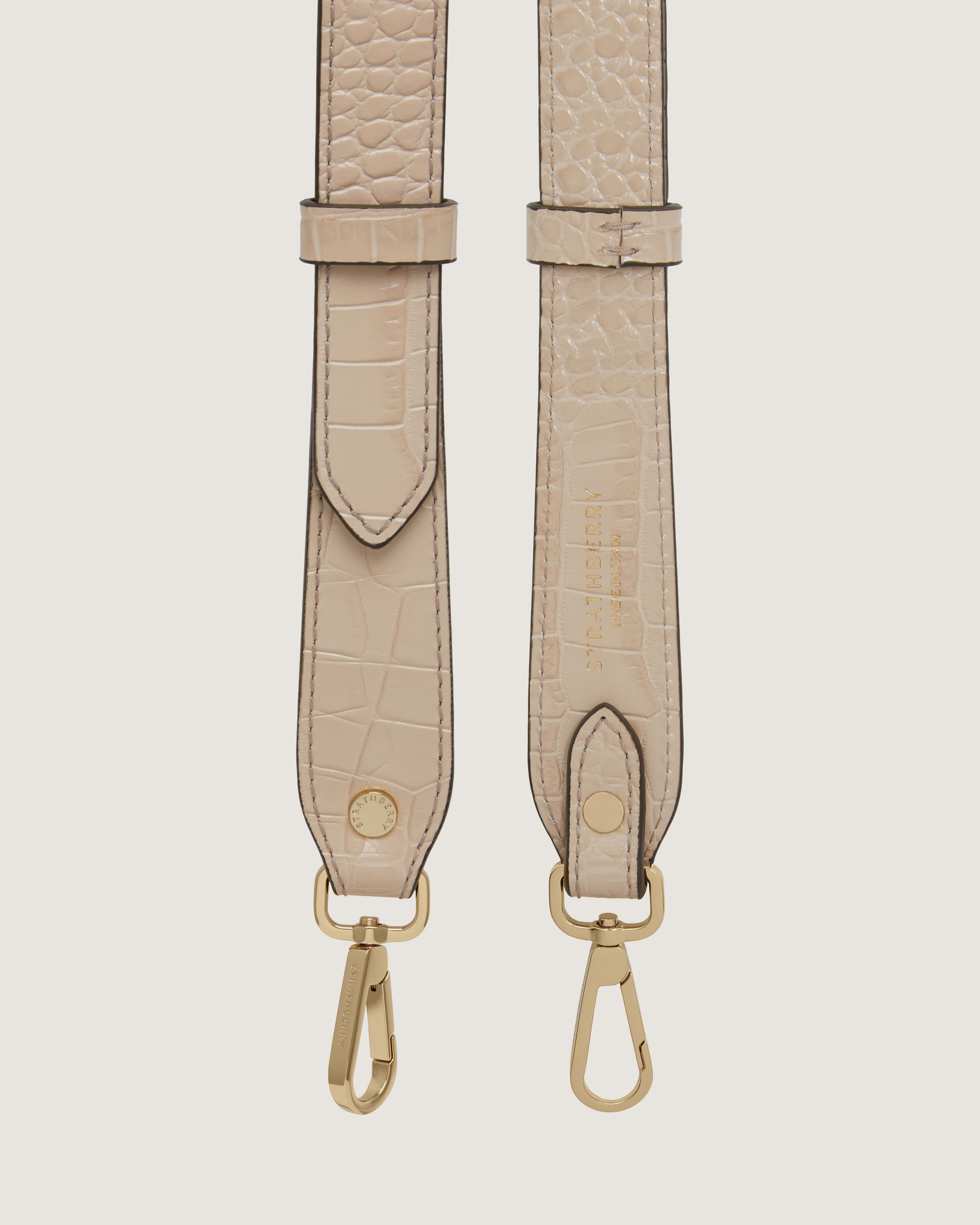 A beige strap with a gold buckle on it