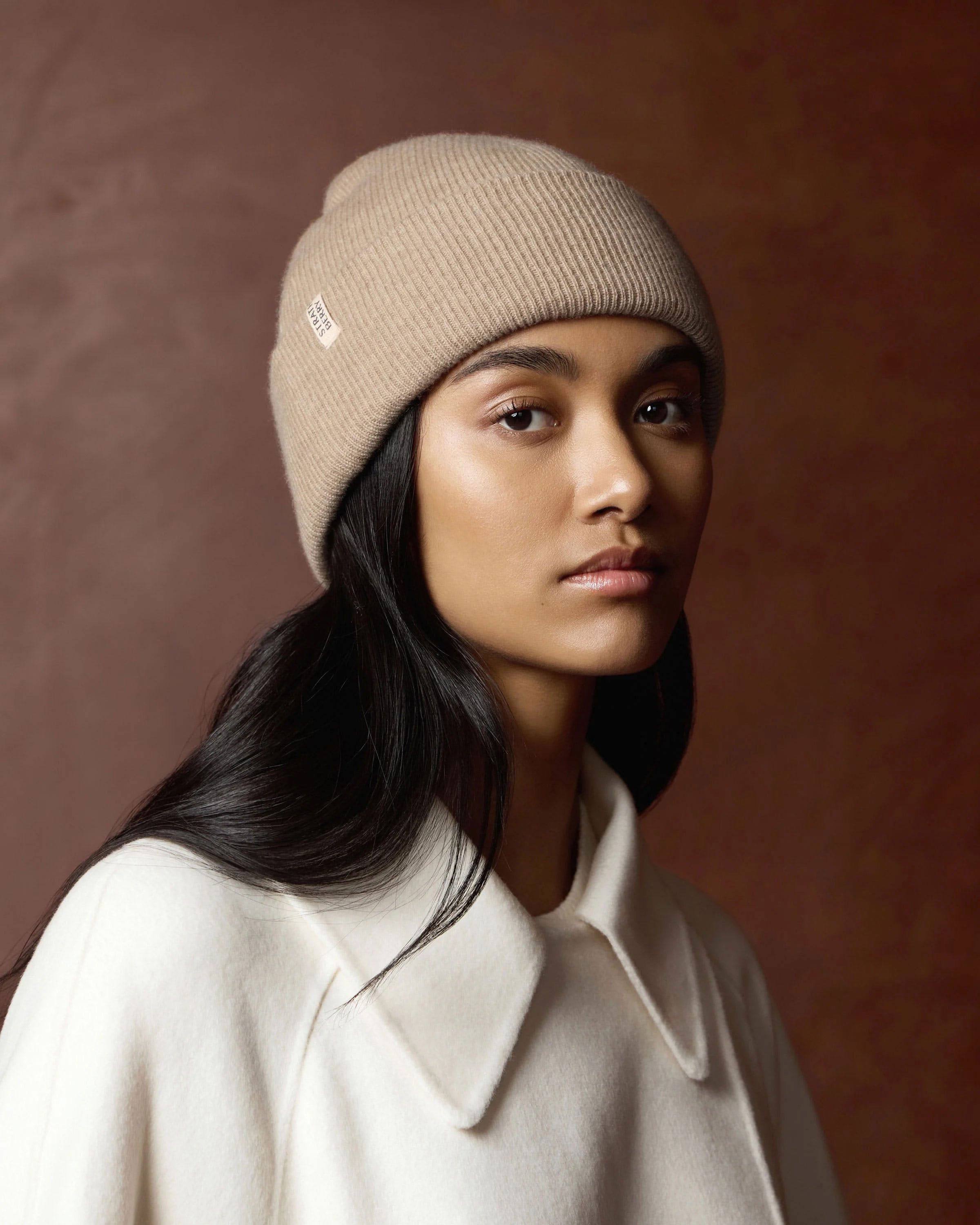 A woman wearing a white coat and a beige hat