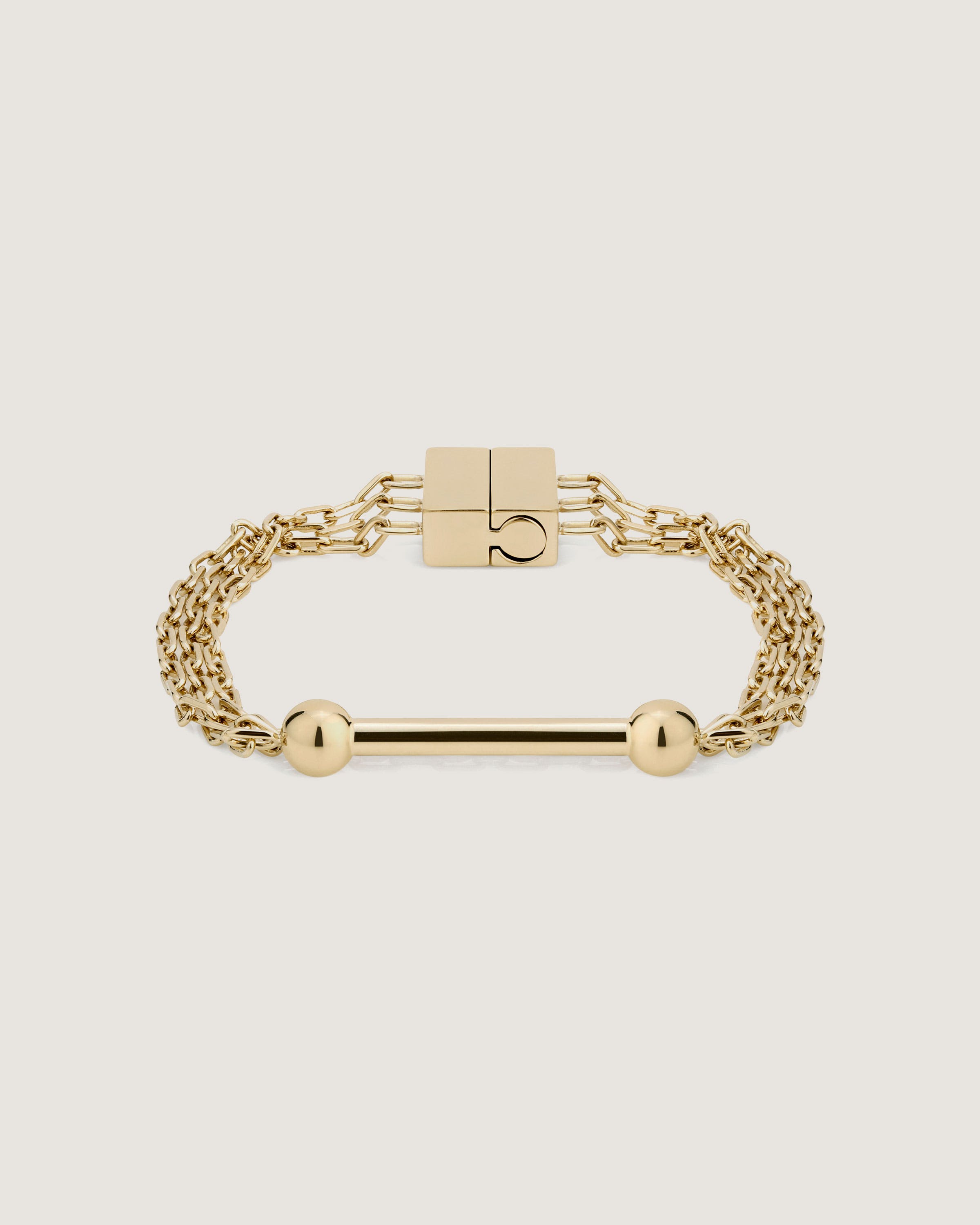 A gold bracelet with two balls and a bar