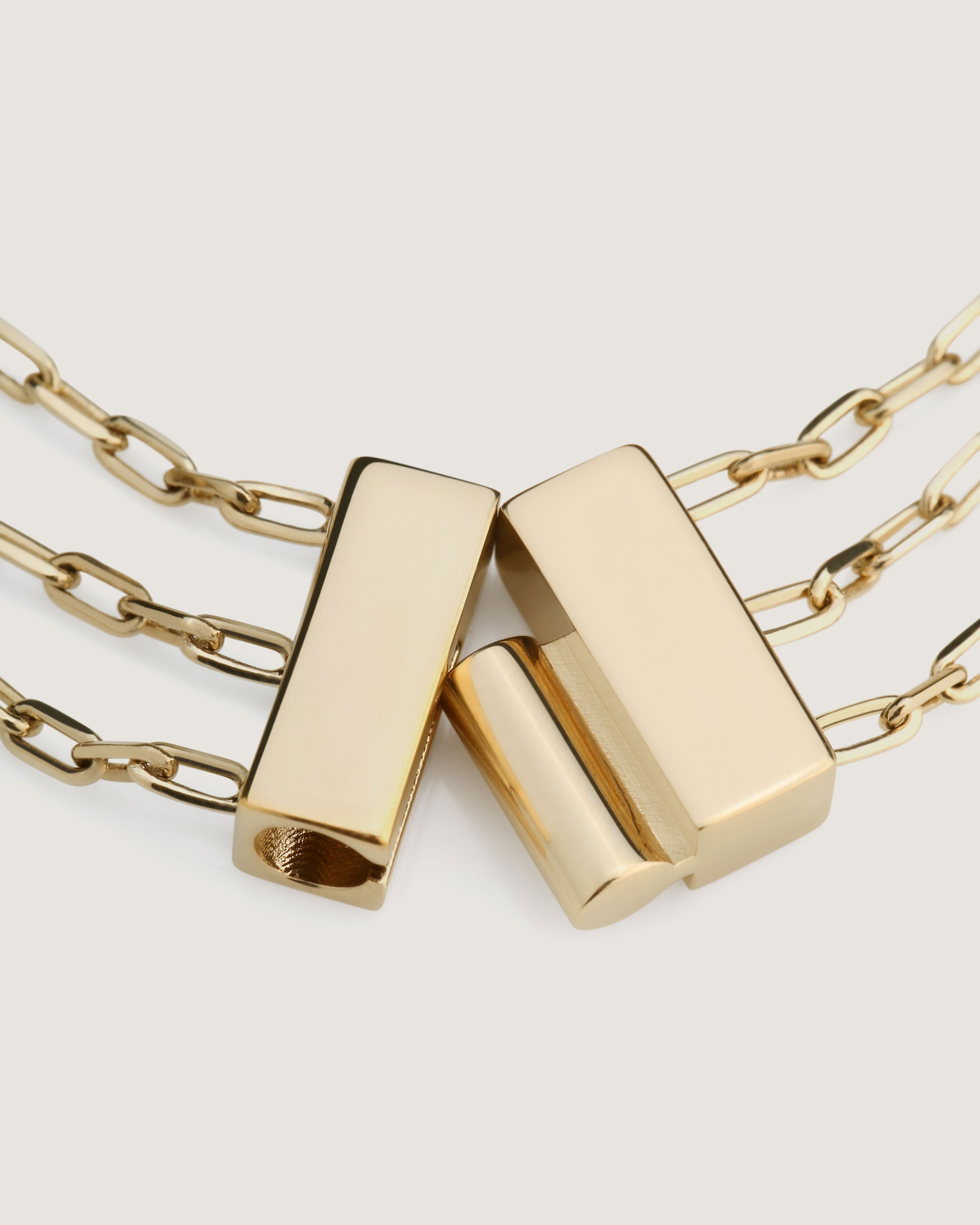 A pair of gold toned necklaces on a white background