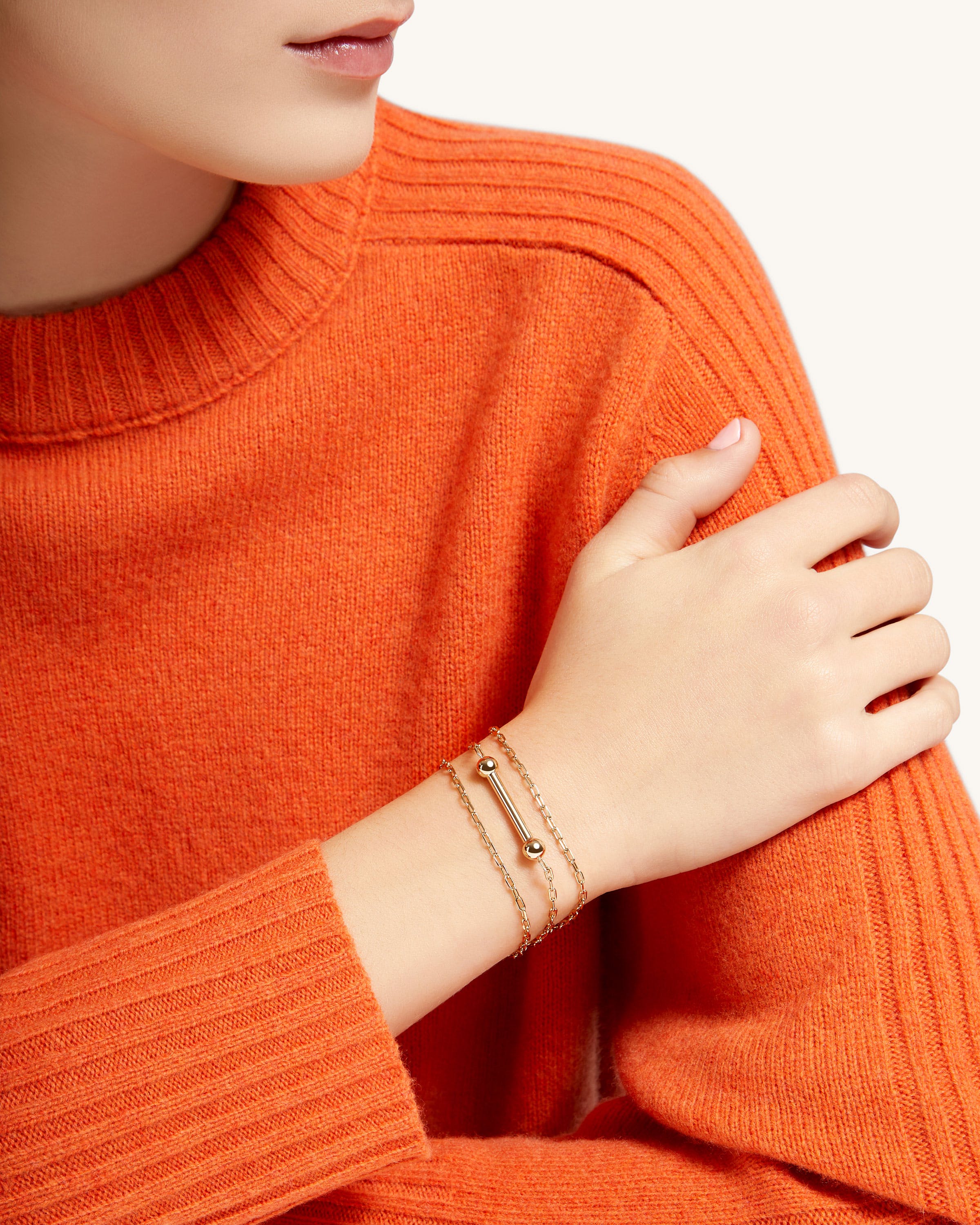 A woman wearing an orange sweater and bracelet