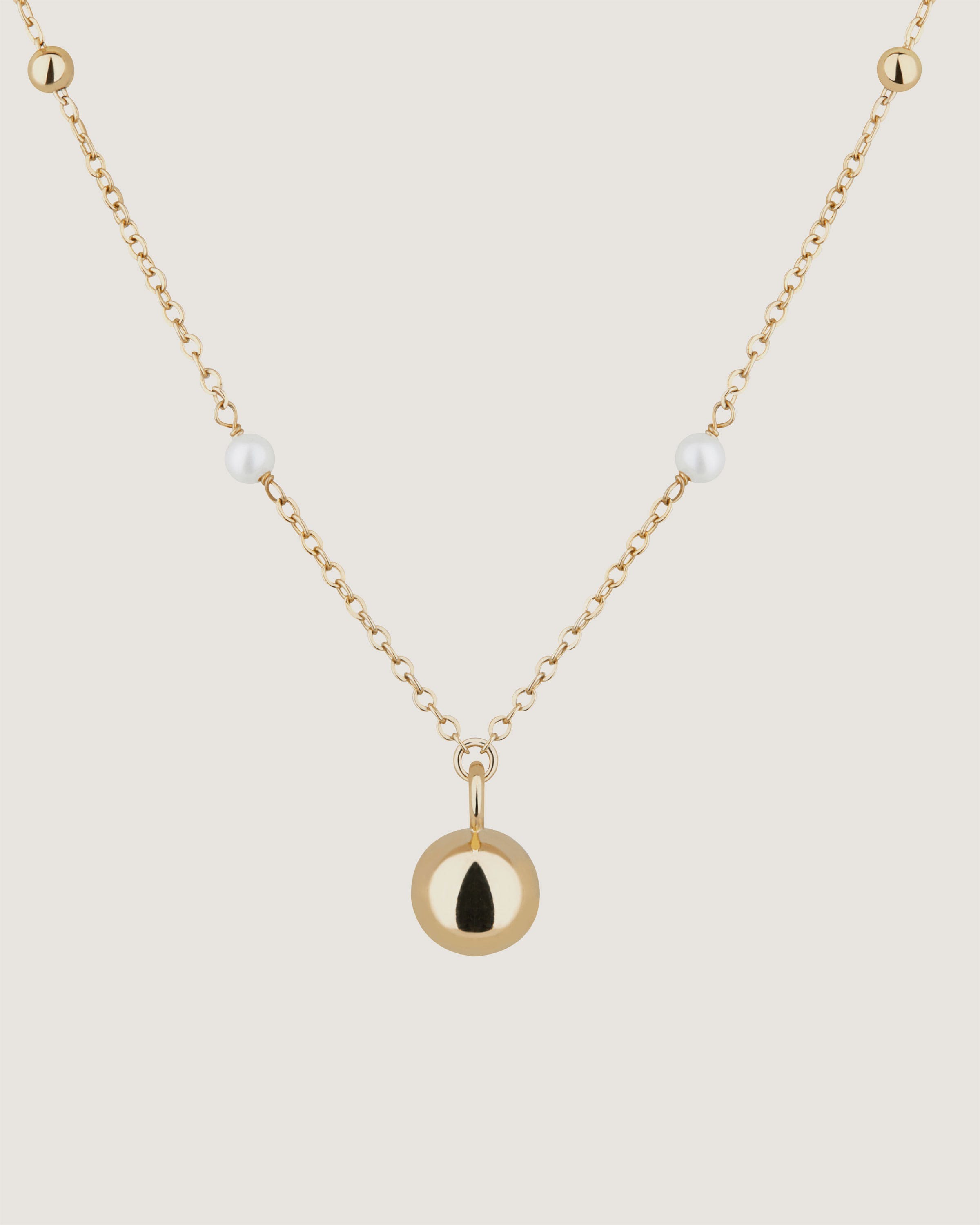 A gold necklace with a black tear on it