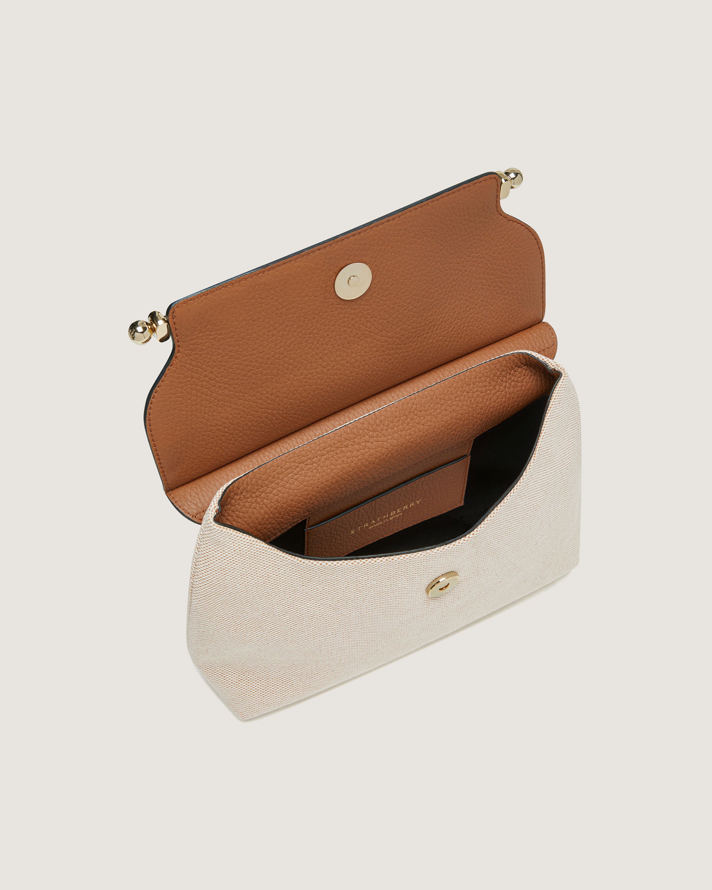 A white and tan purse with a brown handle