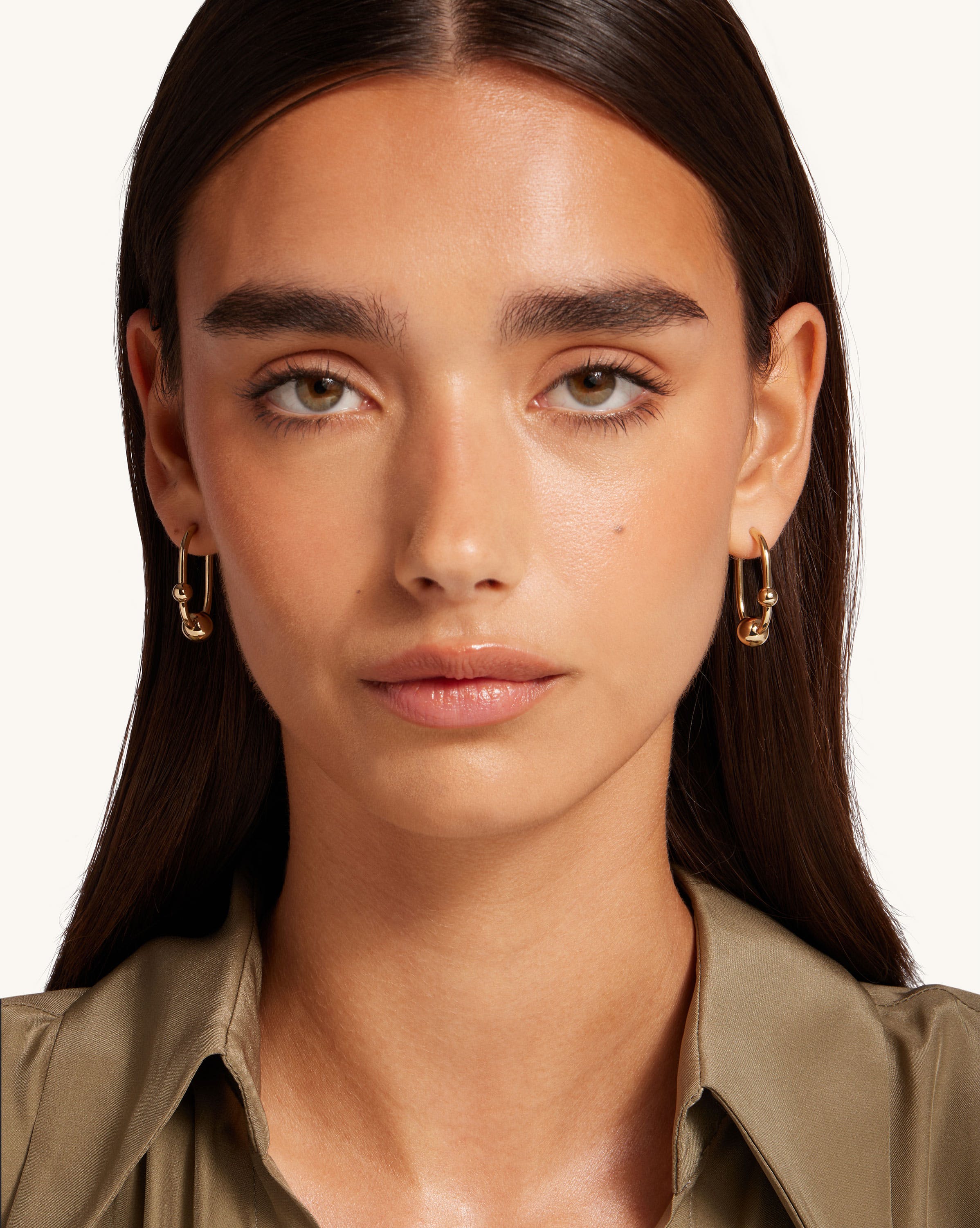 A woman wearing gold earrings and a shirt