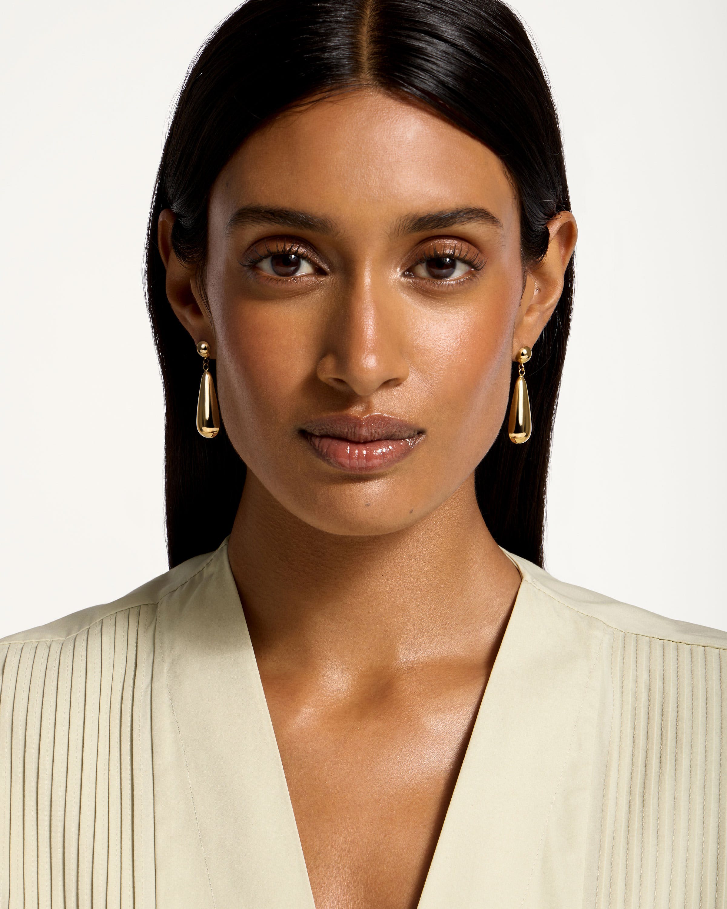 A woman in a white shirt and gold earrings