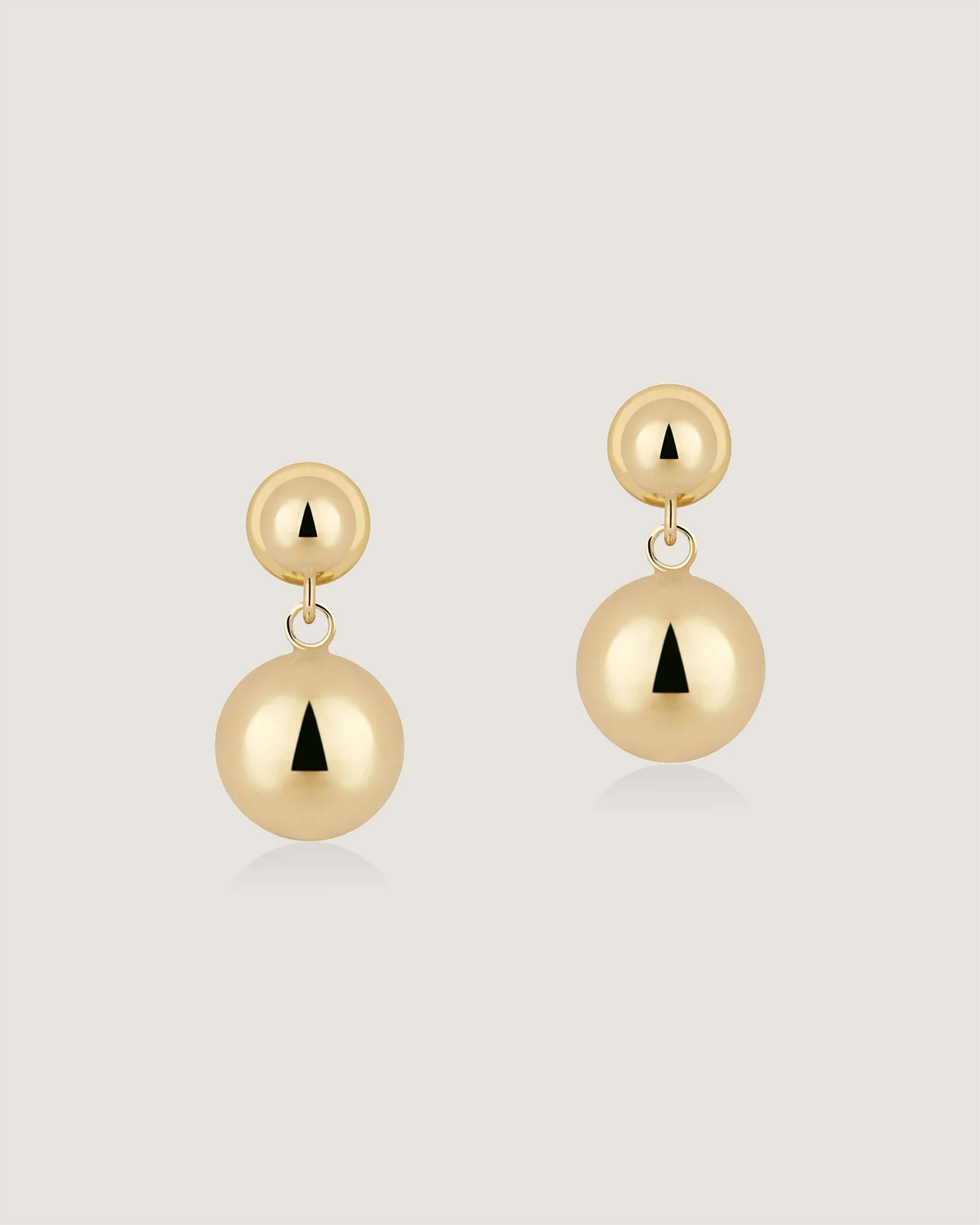 A pair of gold earrings on a white background