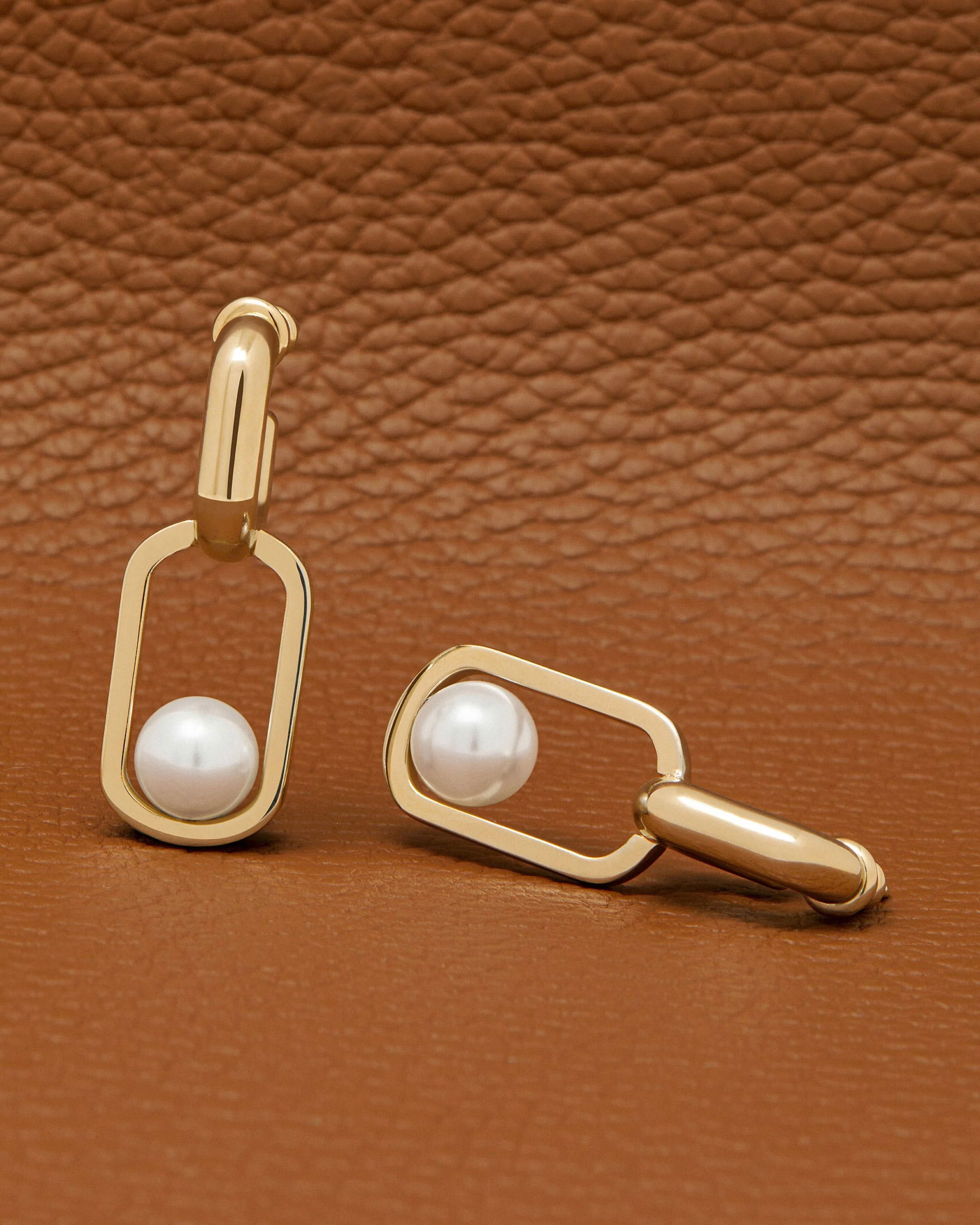 A pair of earrings with pearls on a brown leather background