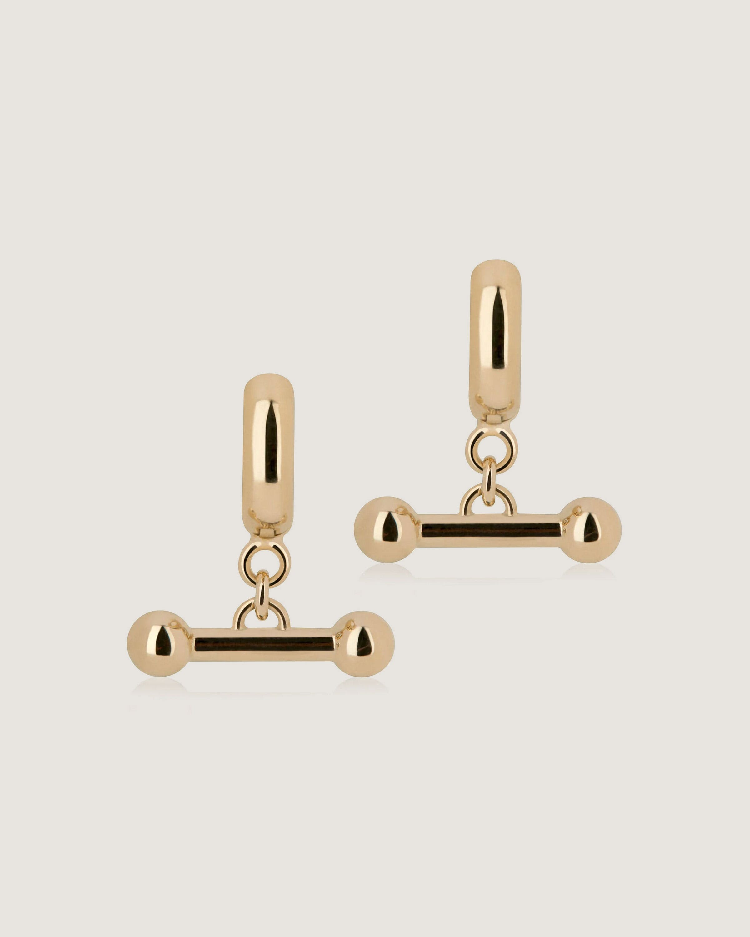 A pair of gold toned earrings on a white background