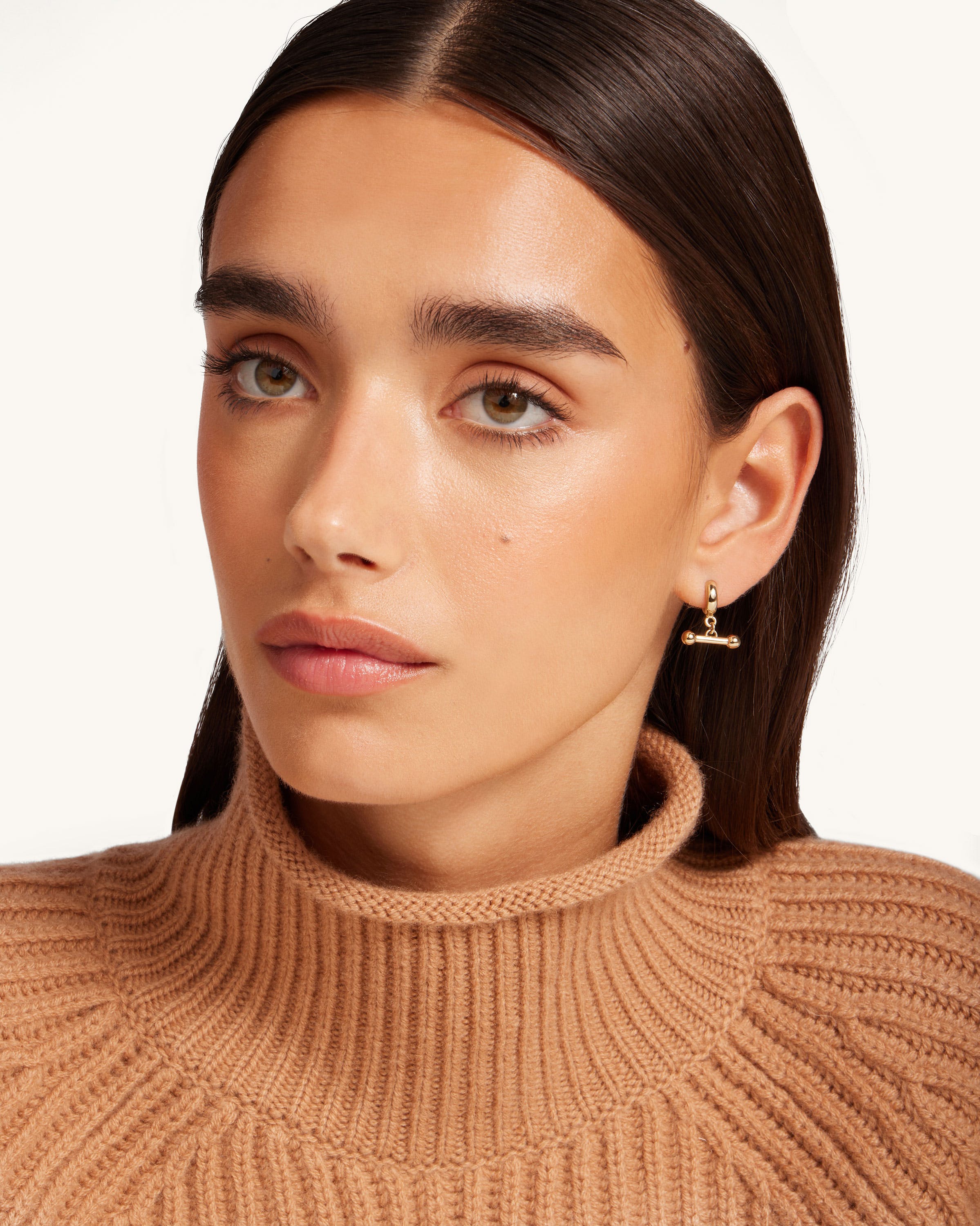 A woman wearing a turtle neck sweater and earrings