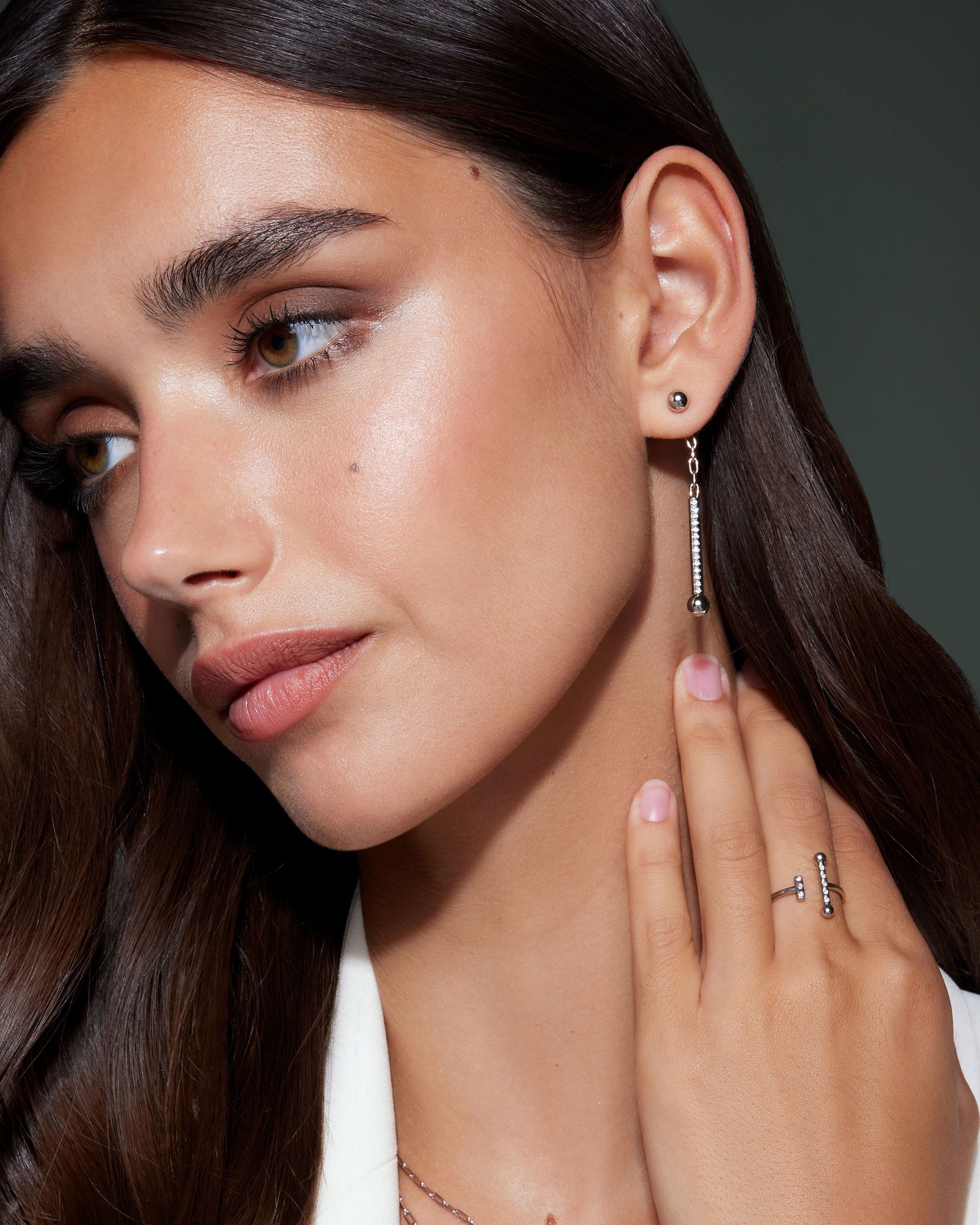 A close up of a person wearing a necklace and earrings