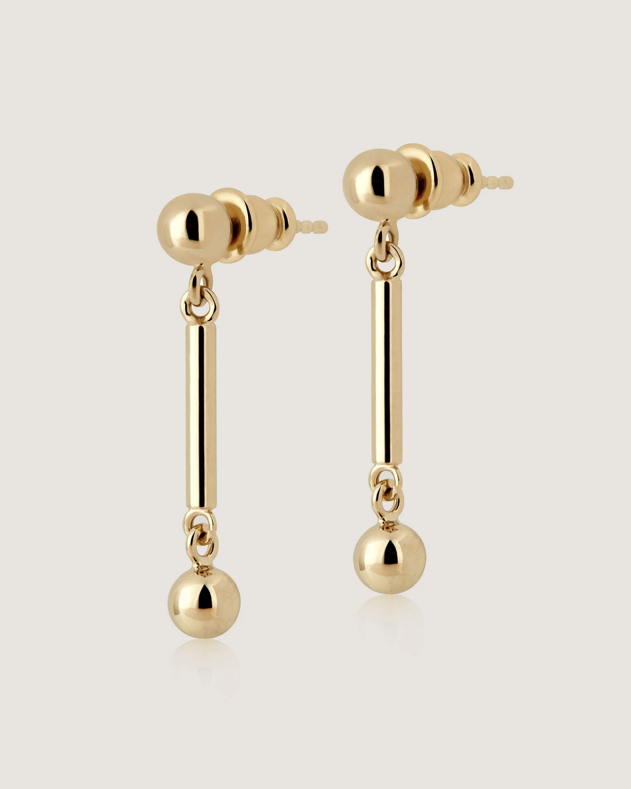 A pair of gold earrings with a ball and chain