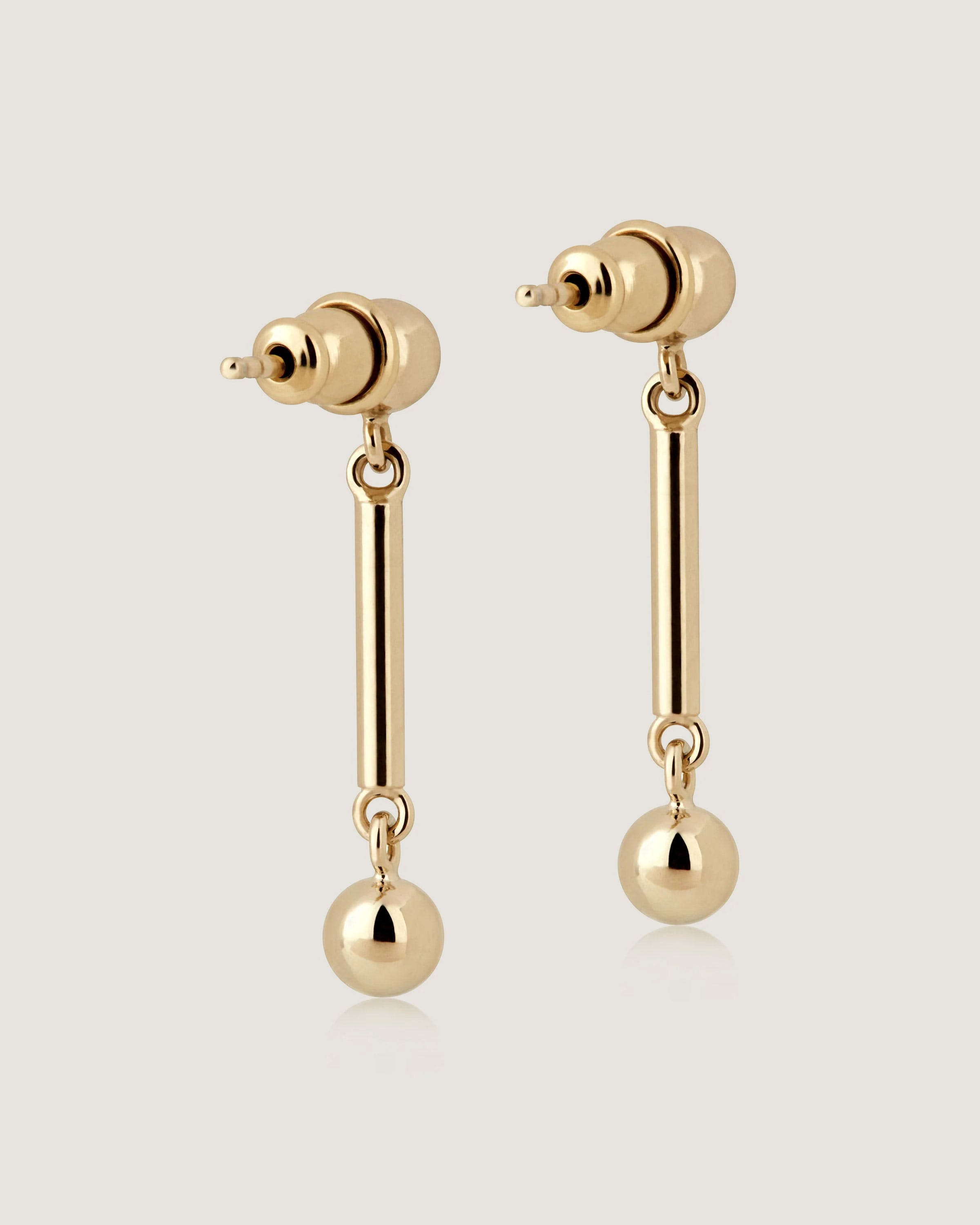 A pair of gold earrings with a ball and a bar