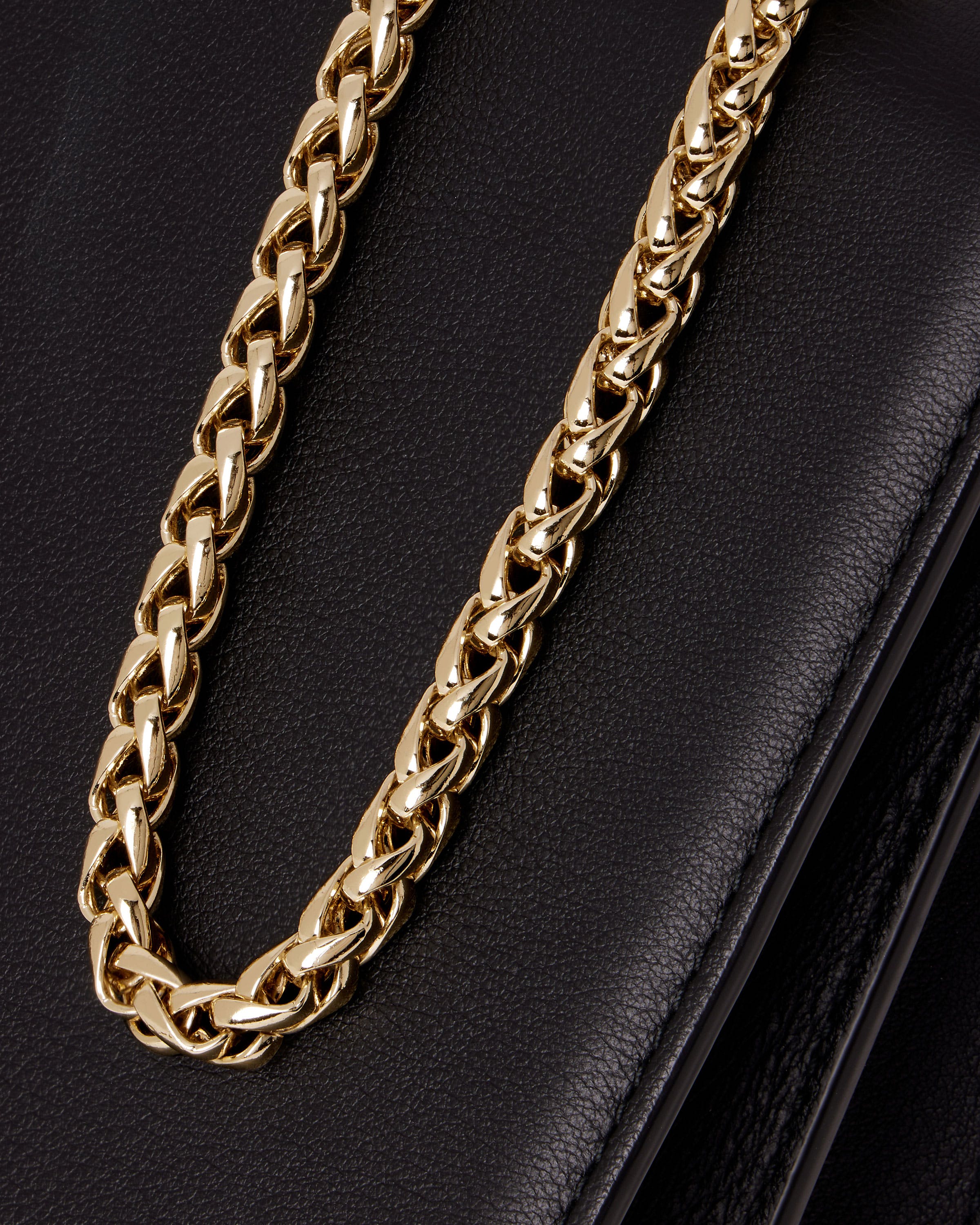 A close up of a gold chain on a black purse