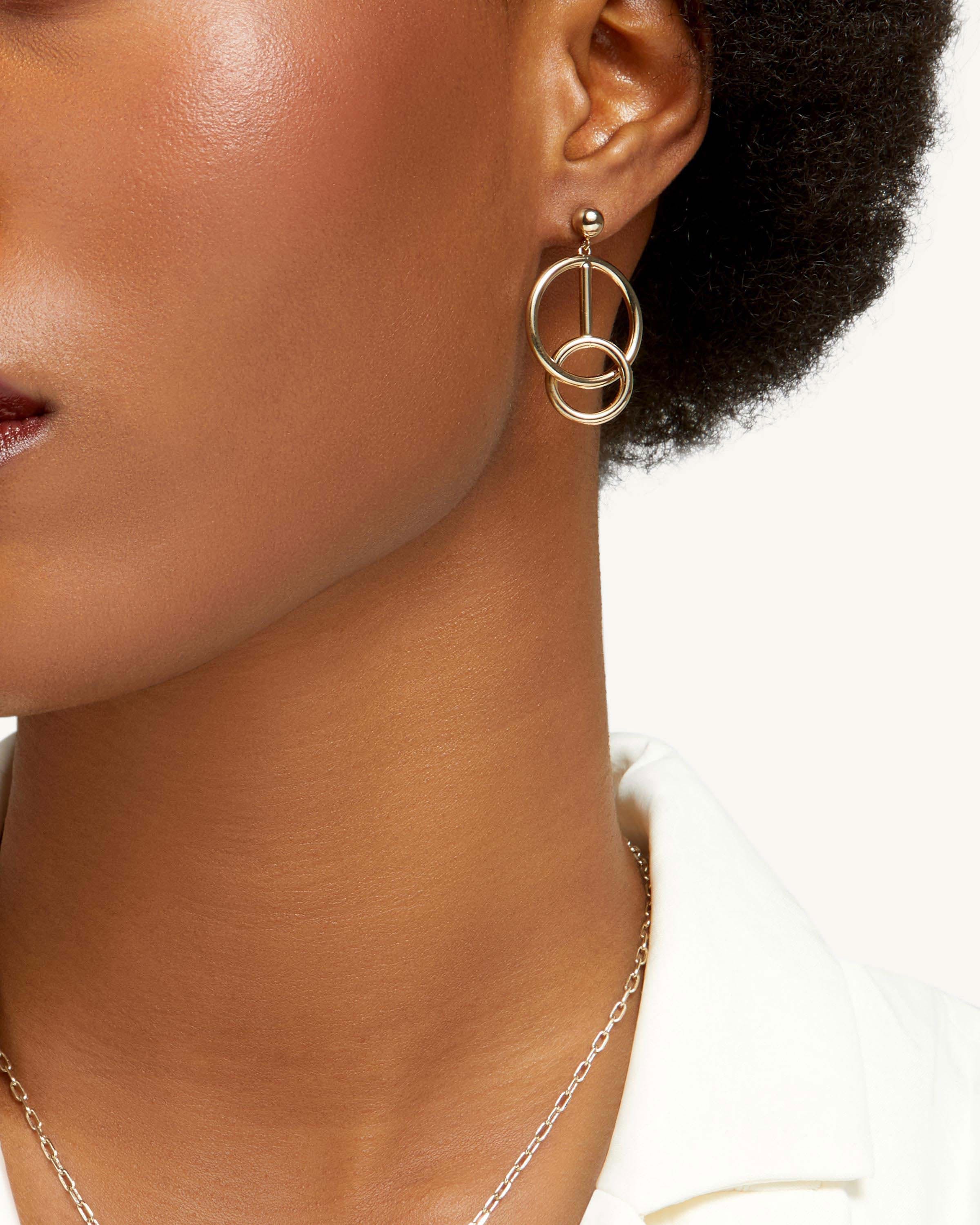 A close up of a woman wearing a necklace and earrings