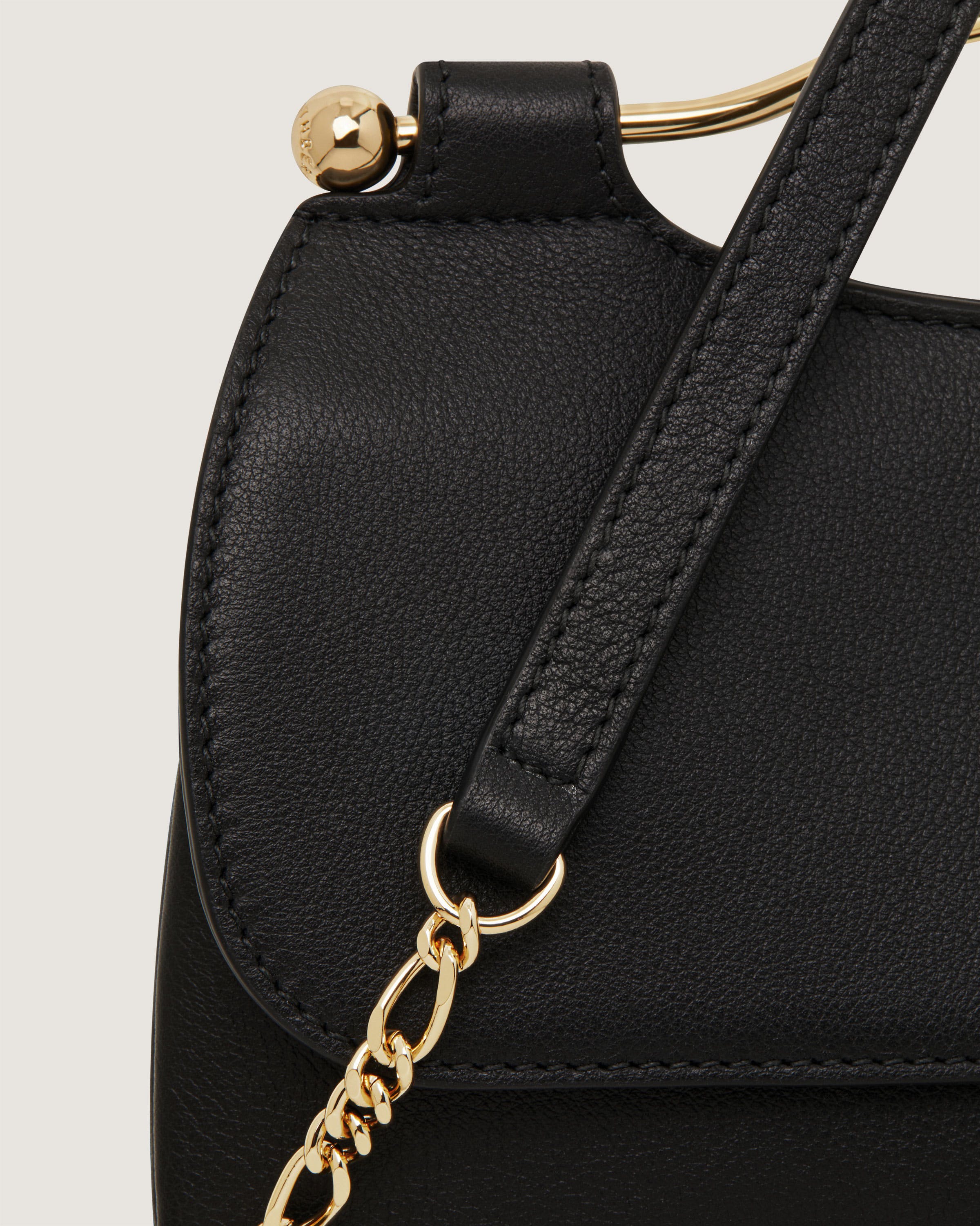 A black handbag with a gold chain hanging from it