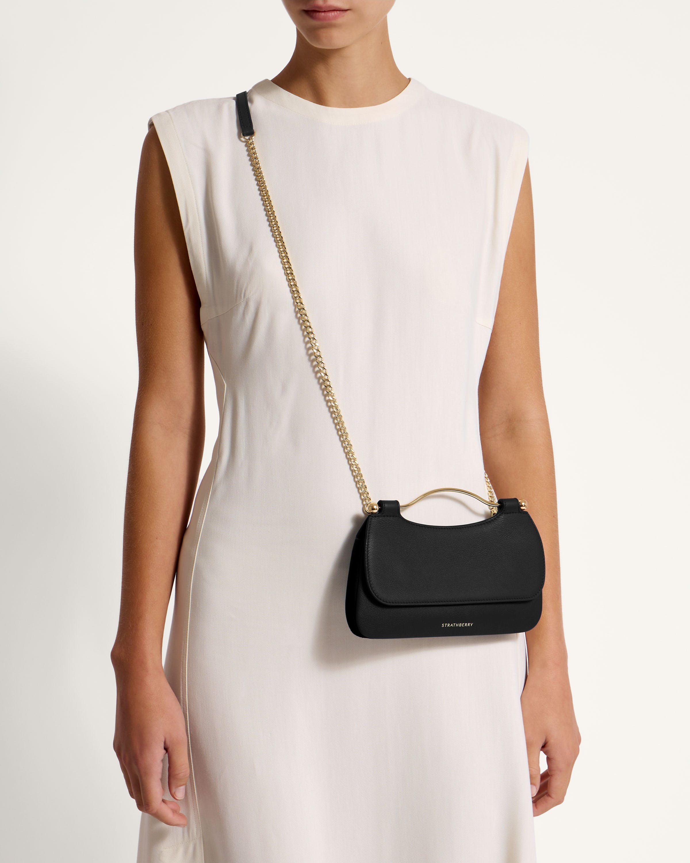 A woman in a white dress holding a black purse